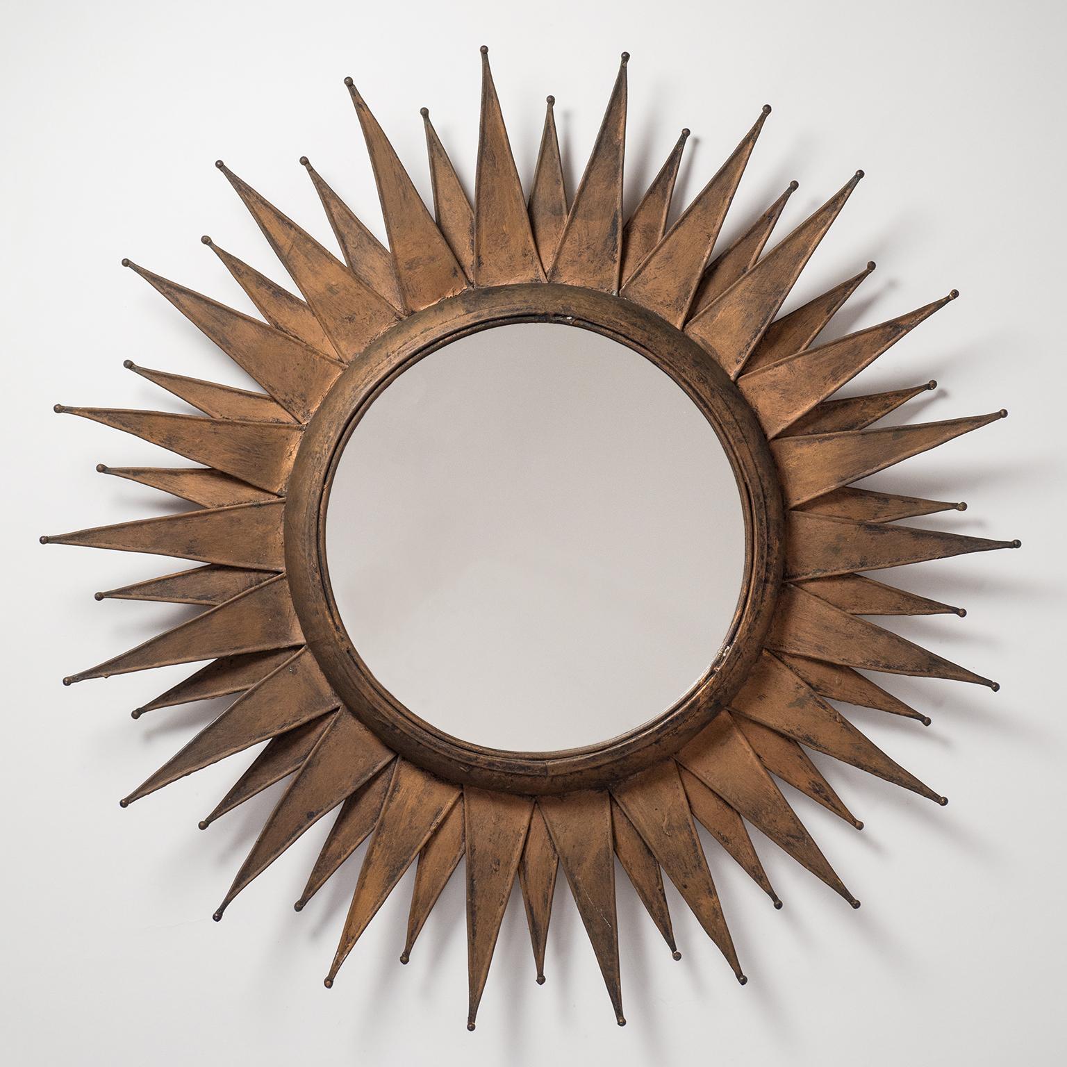 Fantastic artisanal French sunburst mirror from the 1960-1970s. Two layers of bold soldered sheet metal lacquered in copper paint. This piece combines a Brutalist rawness with midcentury sophistication to create a very unique sculptural item. Very