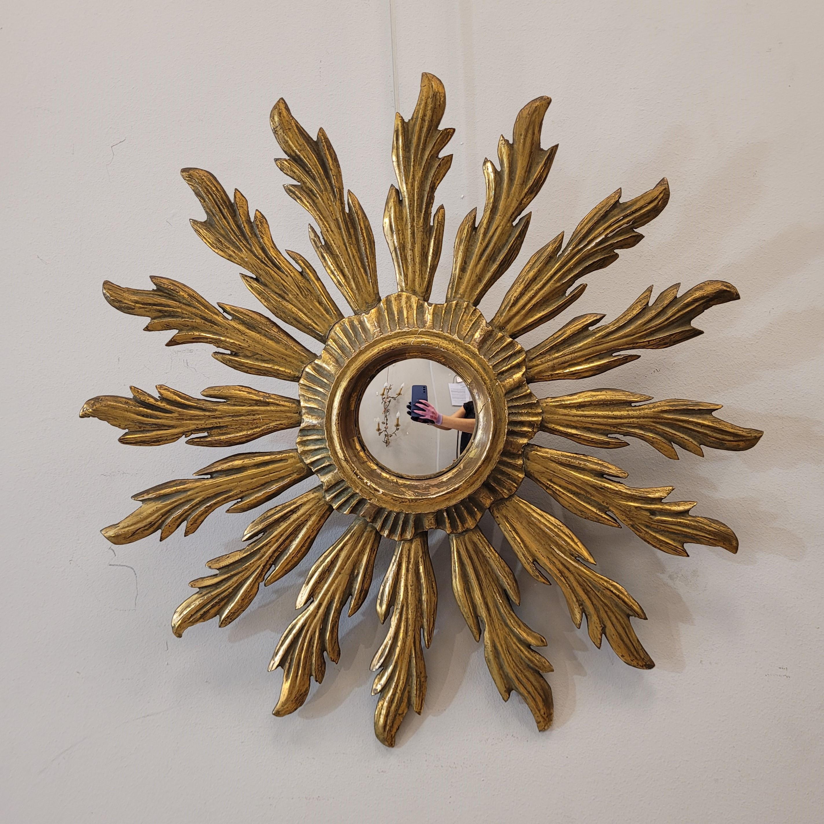Bellissimo specchio antico in legno dorato con riflessi del sole. Lo specchio è in legno intagliato a mano, con una patina dorata. Con uno specchio di vetro convesso chiamato oblò. Il legno e il vetro sono in buone condizioni. Risale al 1920-1930