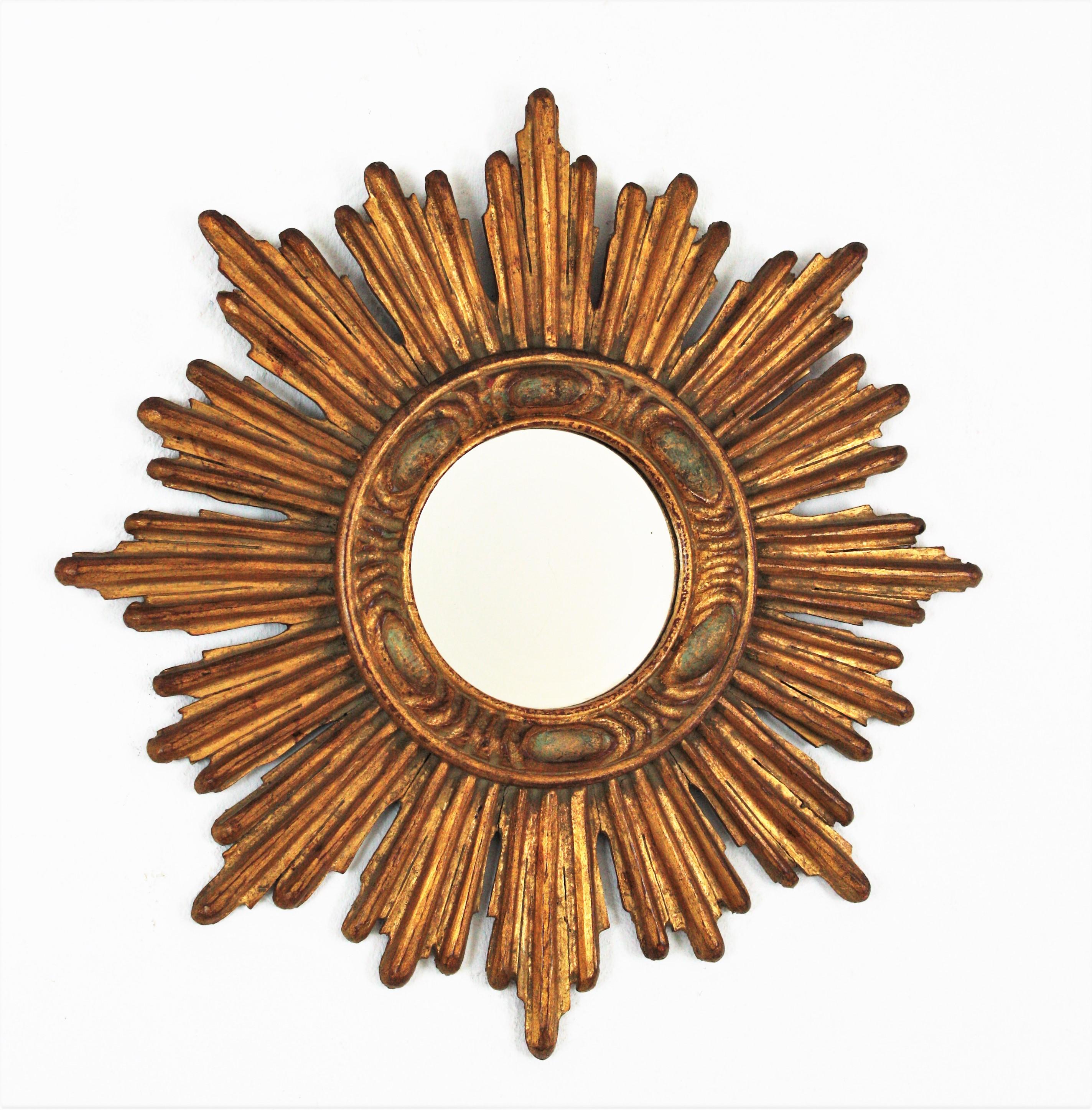 Sunburst mirror, carved wood, gold leaf, France, 1940s.
Elegant sunburst mirror with a frame comprised by alternating rays in two sizes with carving details thorough surrounding the central patterned frame and the round glass. It has a dramatic