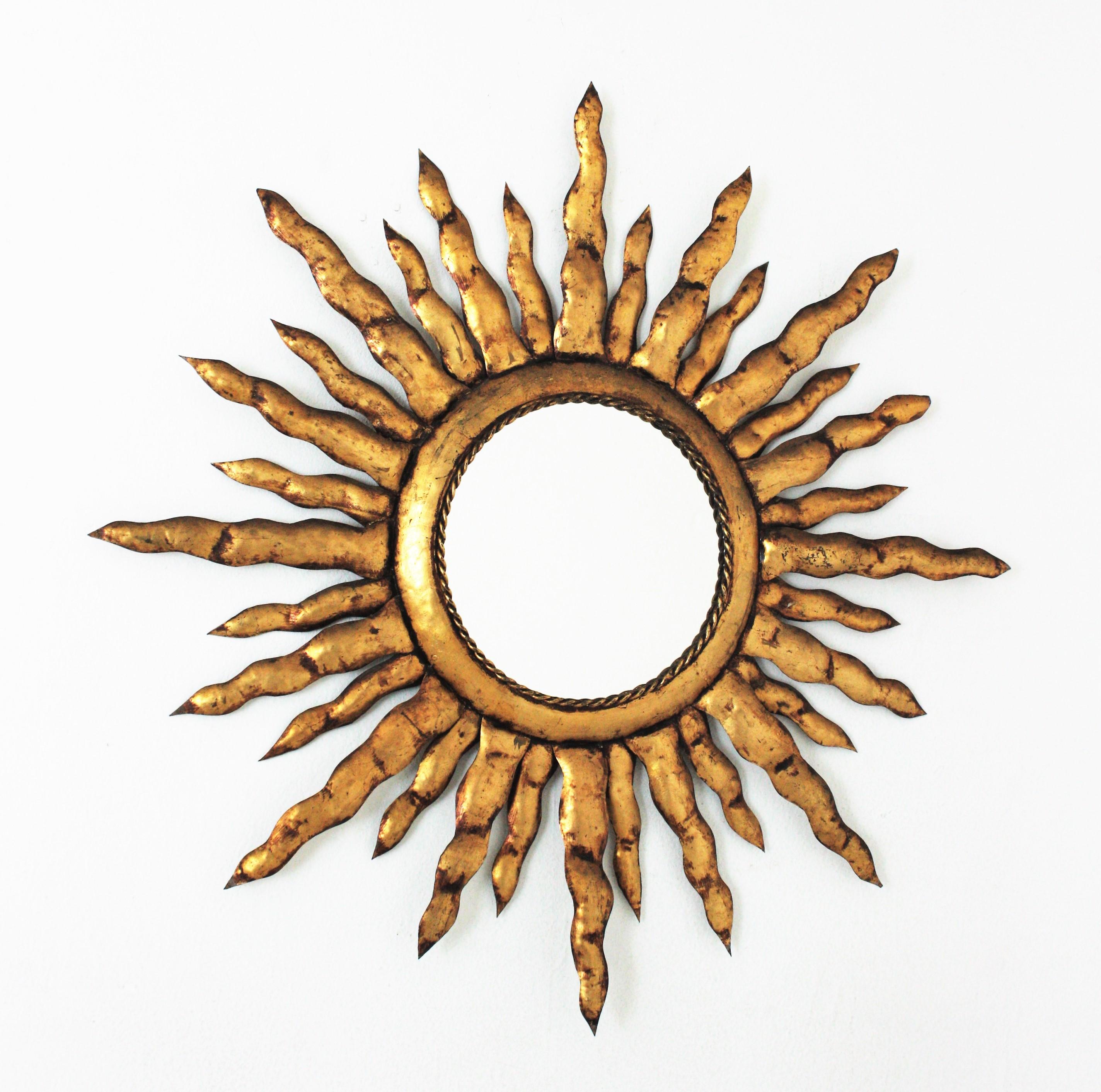 Handcrafted large sunburst mirror, gold leaf, gilt iron. France, 1950s.
This gilt metal sunburst miror has alternating rays in two sizes surrounding the central sphere.
This Brutalist sunburst was entirely made with hand forged iron and gilded