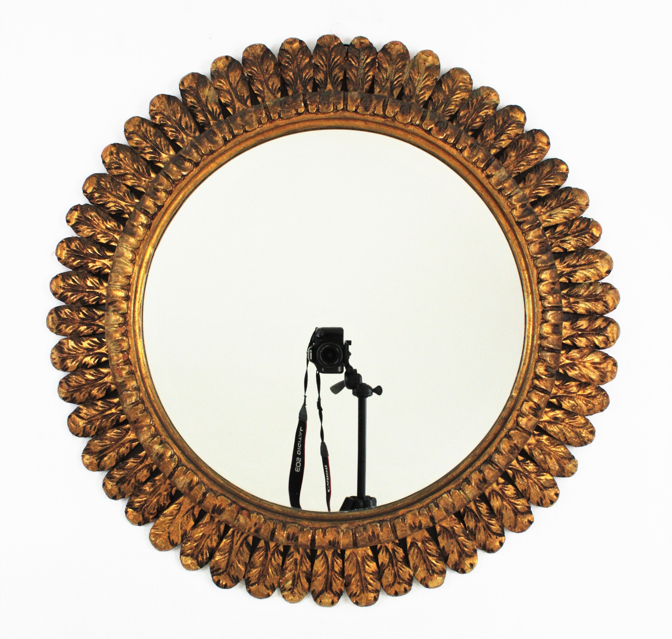 Sunburst Mirror, Gilt Carved Wood, France, 1950s.
A gorgeous hand carved french sunburst mirror with a frame richly decorated by waterleaves and gold leaf gilding.
Manufactured in the Mid-20th century period in the style of Hollywood Regency
