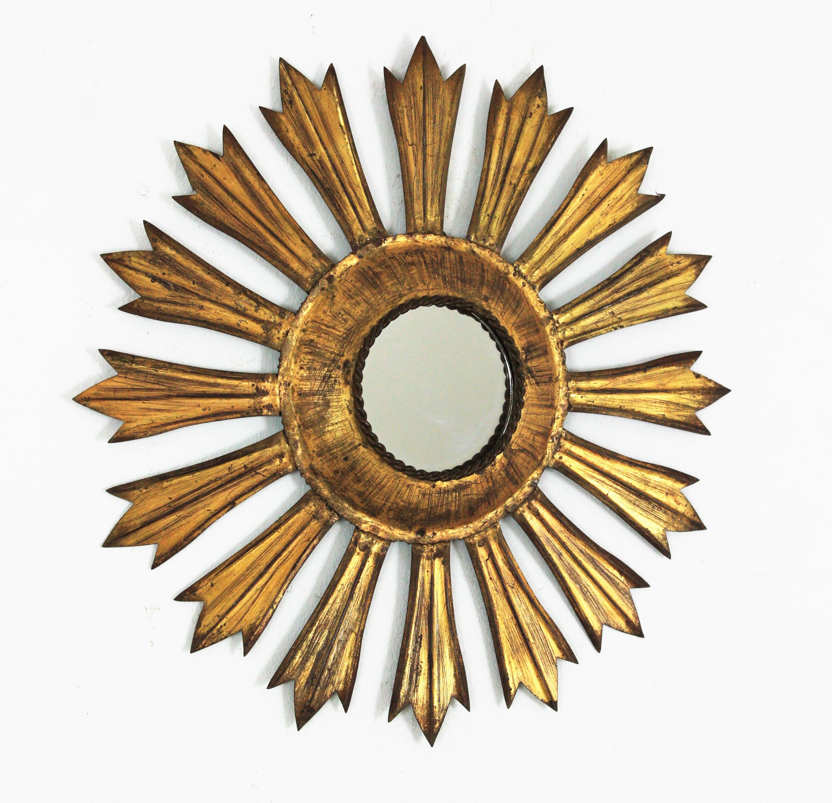 Starburst sunburst wall mirror, Iron, gold leaf, France, 1940s.
This eye-catching handcrafted gilt metal sunburst mirror has a frame with hand cut iron rays surrounding a central small round glass.
It has a terrific patina showing its original