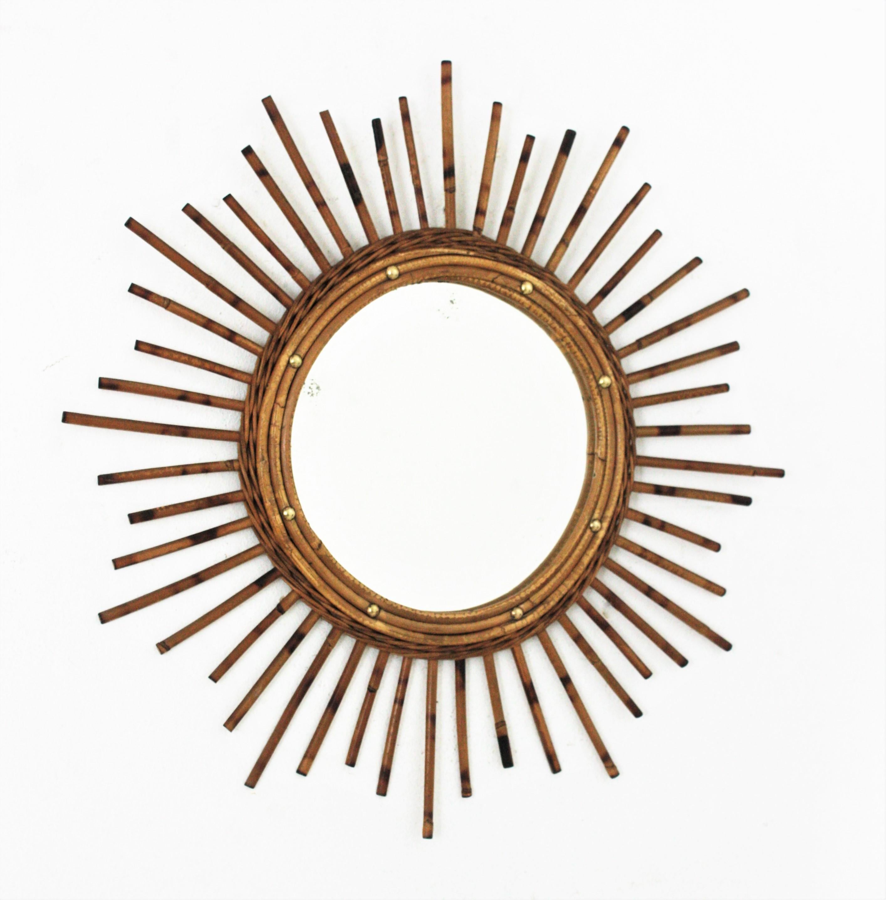 French Riviera Sunburst Starburst Mirror in Rattan, 1960s
Handcrafted starburst sunburst mirror with rattan frame and brass studs.
This eye-catching mediterranean sunburst mirror was handcrafted in France at the sixties and It has all the taste of