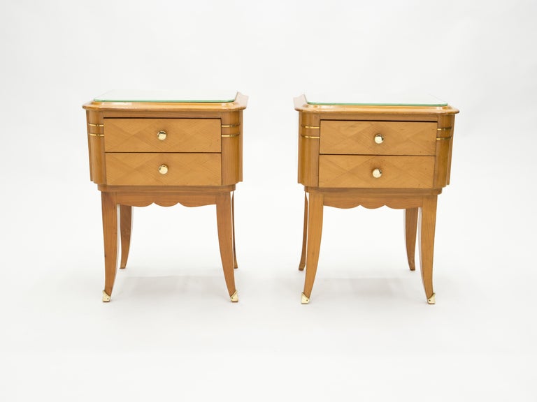 This pair of lined and elegant two drawers nightstands is made from sycamore, with mirror tops, made by Jean Pascaud in the early 1940s. Vintage and sophisticated, typically French Art Deco, they feature brass handles and details, with sinuous saber