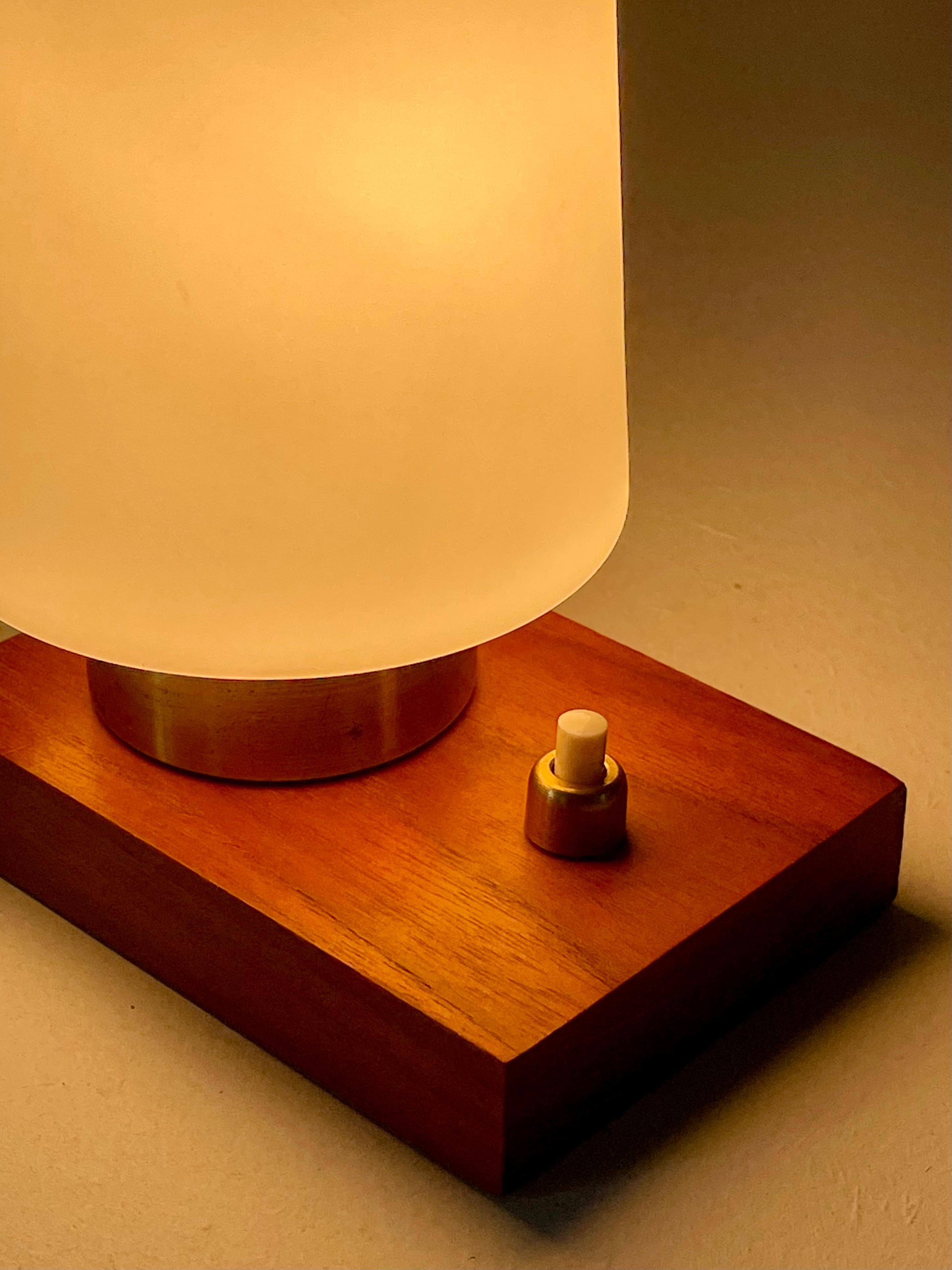 A charming small table or bedside lamp, France, circa 1960.

Composed of a rectangular wooden base, a brass mount, and a cylindrical frosted glass shade, this lamp combines warm materials and clean lines typical of mid-century French design.

The