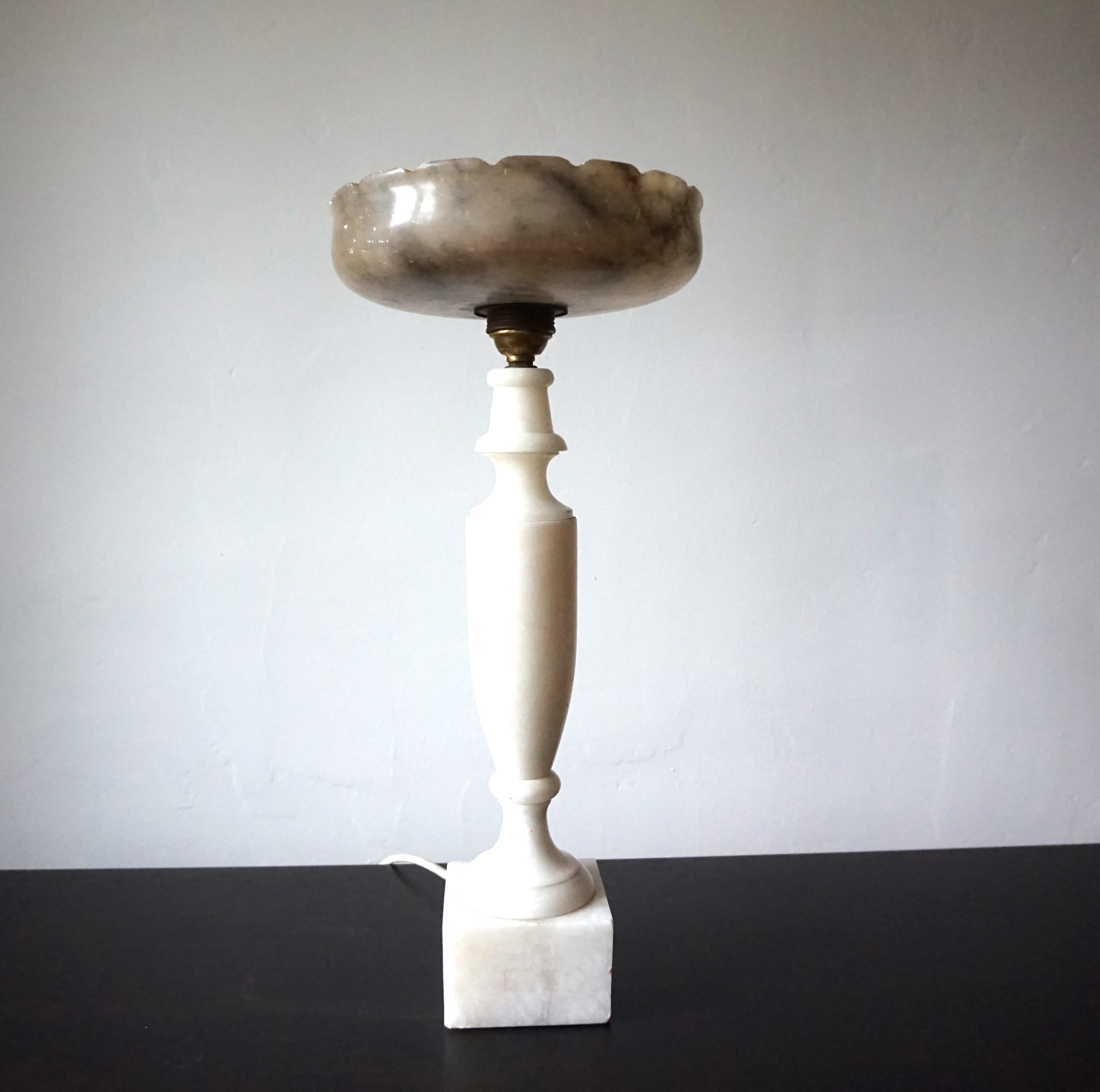 This extraordinary table lamp with a marble base in the shape of a narrow amphora, standing on a square base and a marble bowl, comes in very good condition. The light marble of the base harmonizes beautifully with the lamp head, which consists of a
