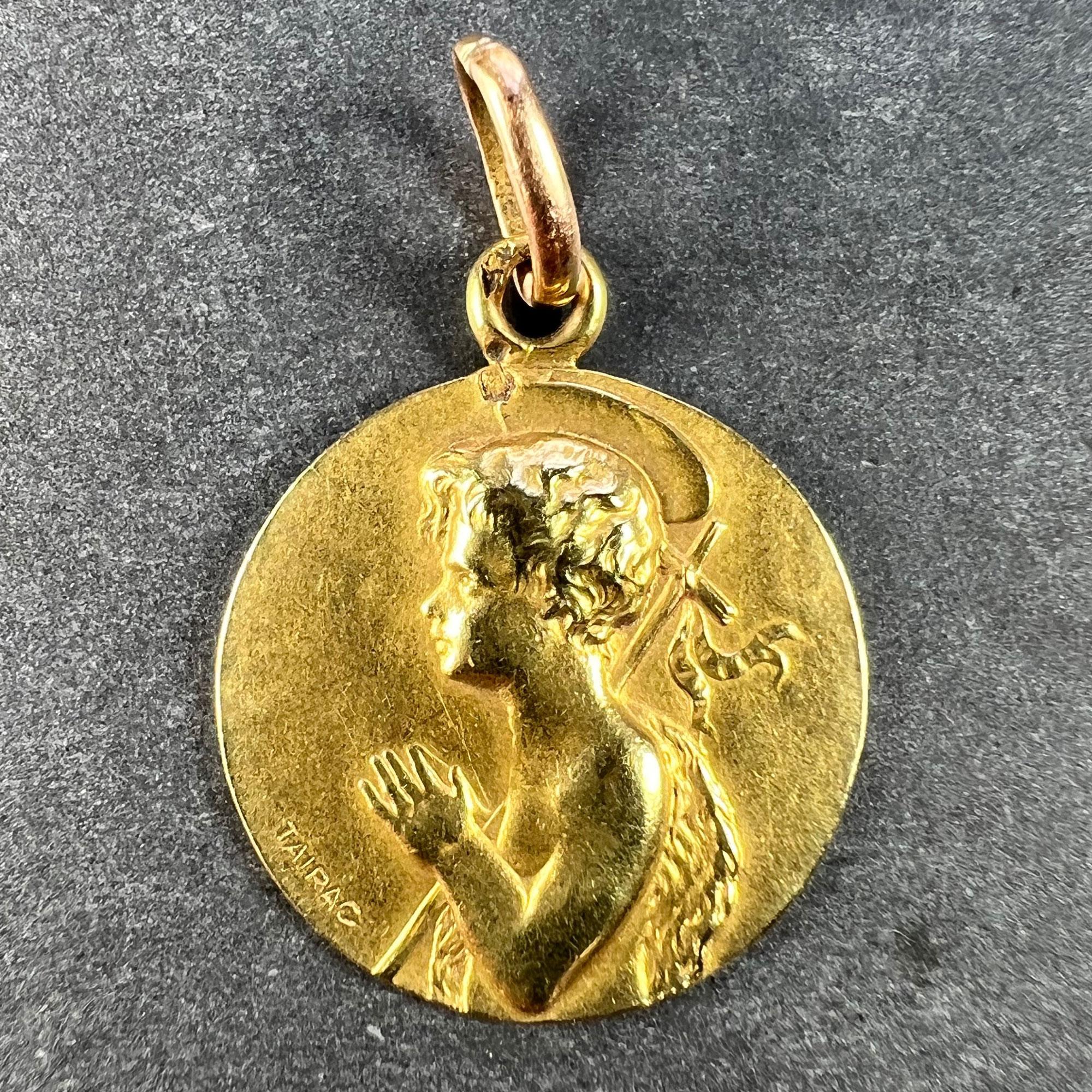 A French 18 karat (18K) yellow gold charm pendant designed as a medal representing Saint John the Baptist as a child with a cross and a sheepskin over one shoulder. Signed Tairac, stamped with the eagle's head for French manufacture and 18 karat