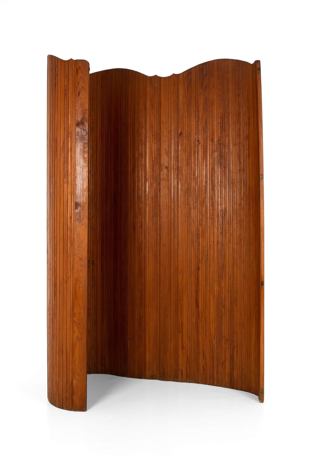 Ein eleganter Tambour-Raumteiler aus Kiefernholz des französischen Designhauses S.N.S.A.

Mit einem unsichtbaren Draht, der die Lamellen miteinander verbindet, lässt sich der Paravent in verschiedenen Formen aufstellen.

Der Paravent ist ein