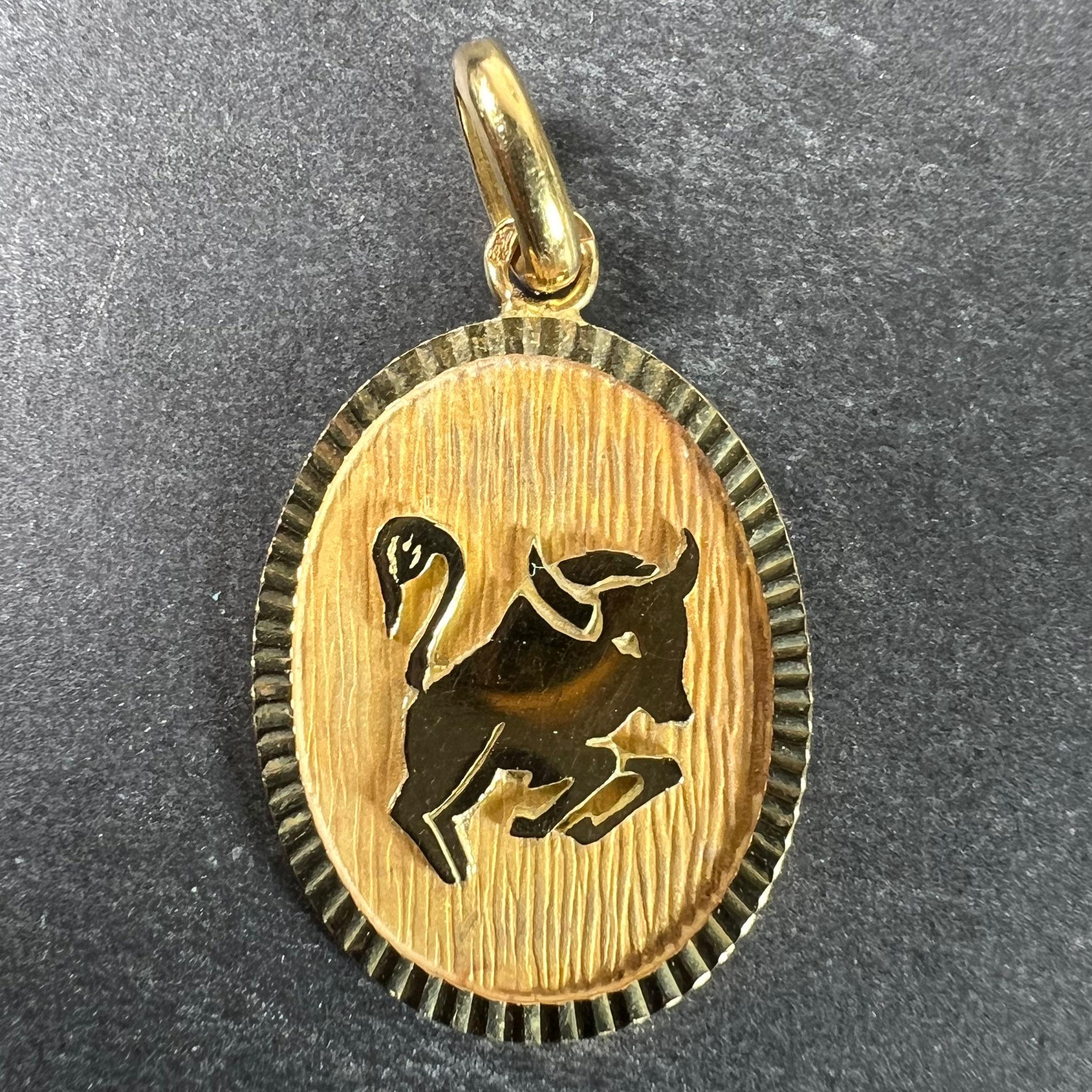 A French 18 karat (18K) yellow gold charm pendant designed as an oval medal with an matt recess depicting a charging bull representing the zodiac star sign of Taurus. Stamped with the eagle’s head for French manufacture and 18 karat gold with an
