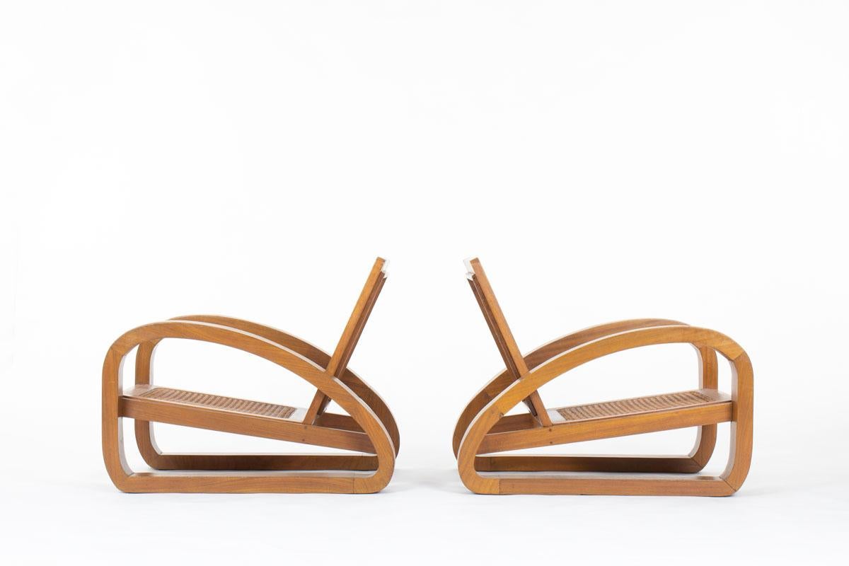 Cette élégante paire de fauteuils a été conçue dans la France des années 1950 et reflète le charme discret du style bohème chic. Chaque chaise présente une structure en teck massif avec une assise et un dossier cannés à la main, offrant à la fois