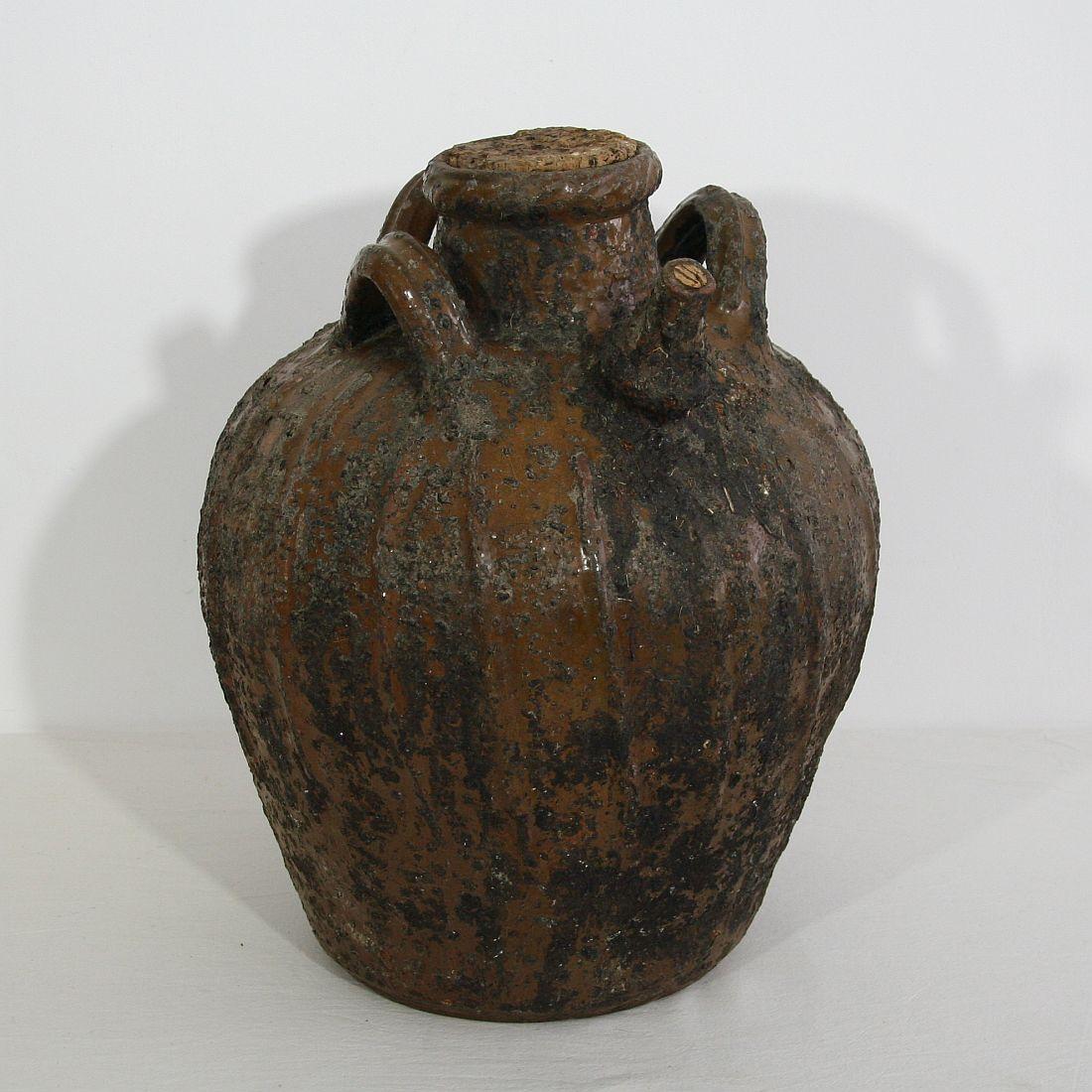 French walnut oil jug from the Auvergne region in France. A large three-handled brown-glazed terracotta storage vessel, with pouring spout. It is a rare piece that once was characteristic for this region in France. The jug is in a good condition