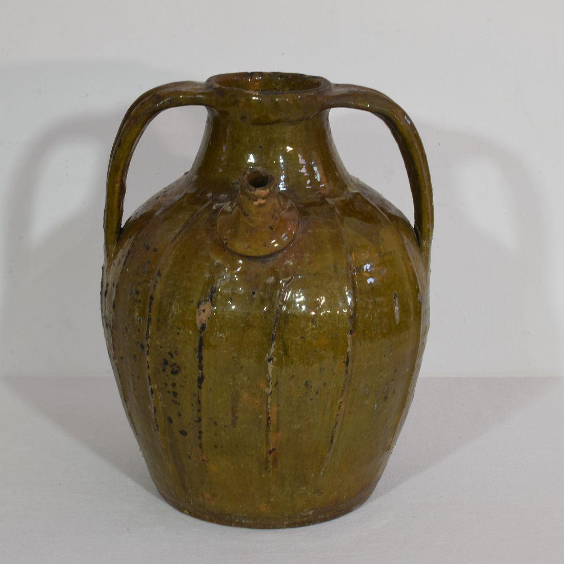 French walnut oil jug from the Auvergne region in France. A large three-handled brown-glazed terracotta storage vessel, with pouring spout. It is a rare piece that once was characteristic for this region in France. The jug is in a good condition