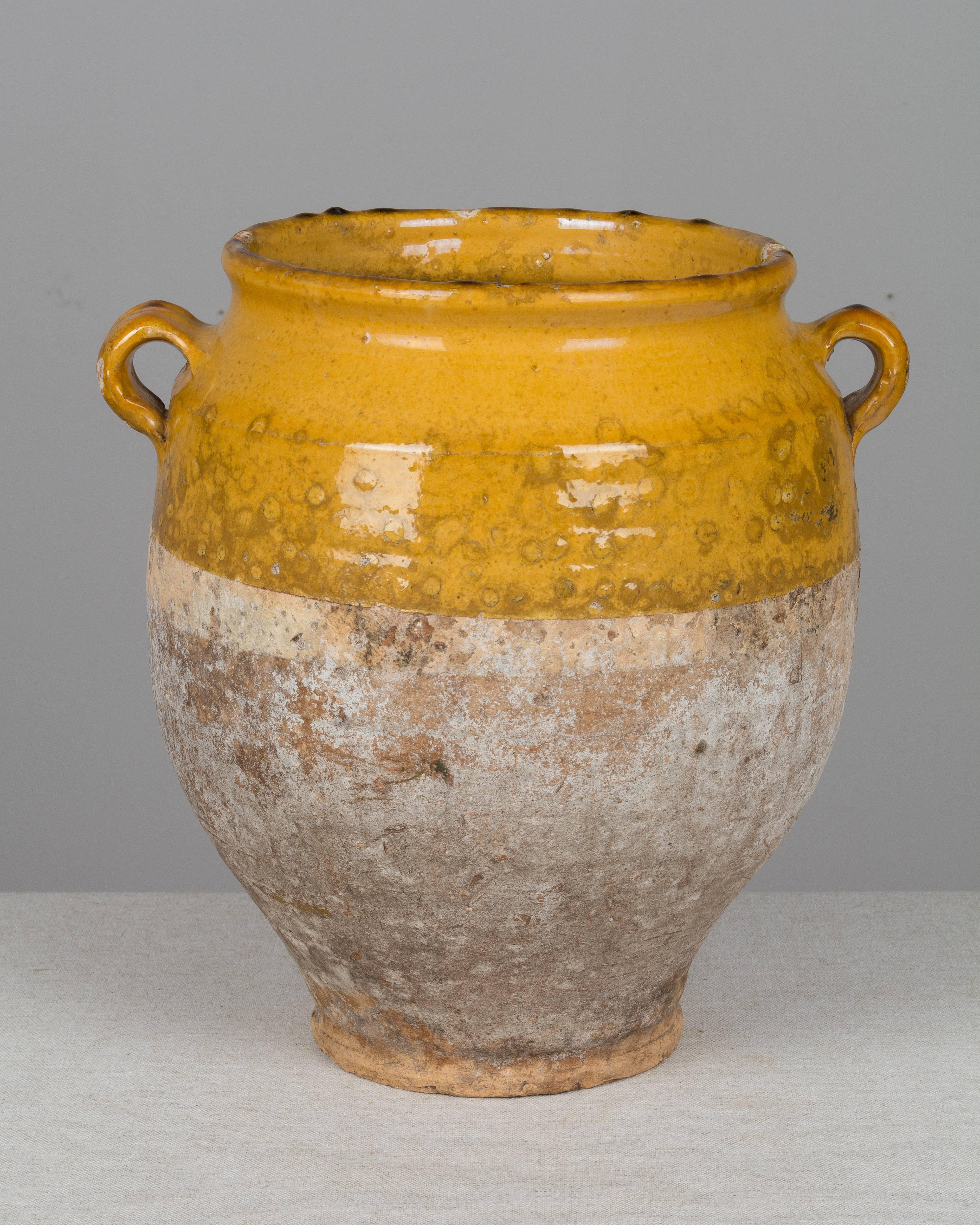 An earthenware confit pot from the Southwest of France with traditional ochre yellow glaze. Beautiful patina. Minor losses. These ordinary earthenware vessels were once used daily in the French country home and have beautiful rustic glazes of green,