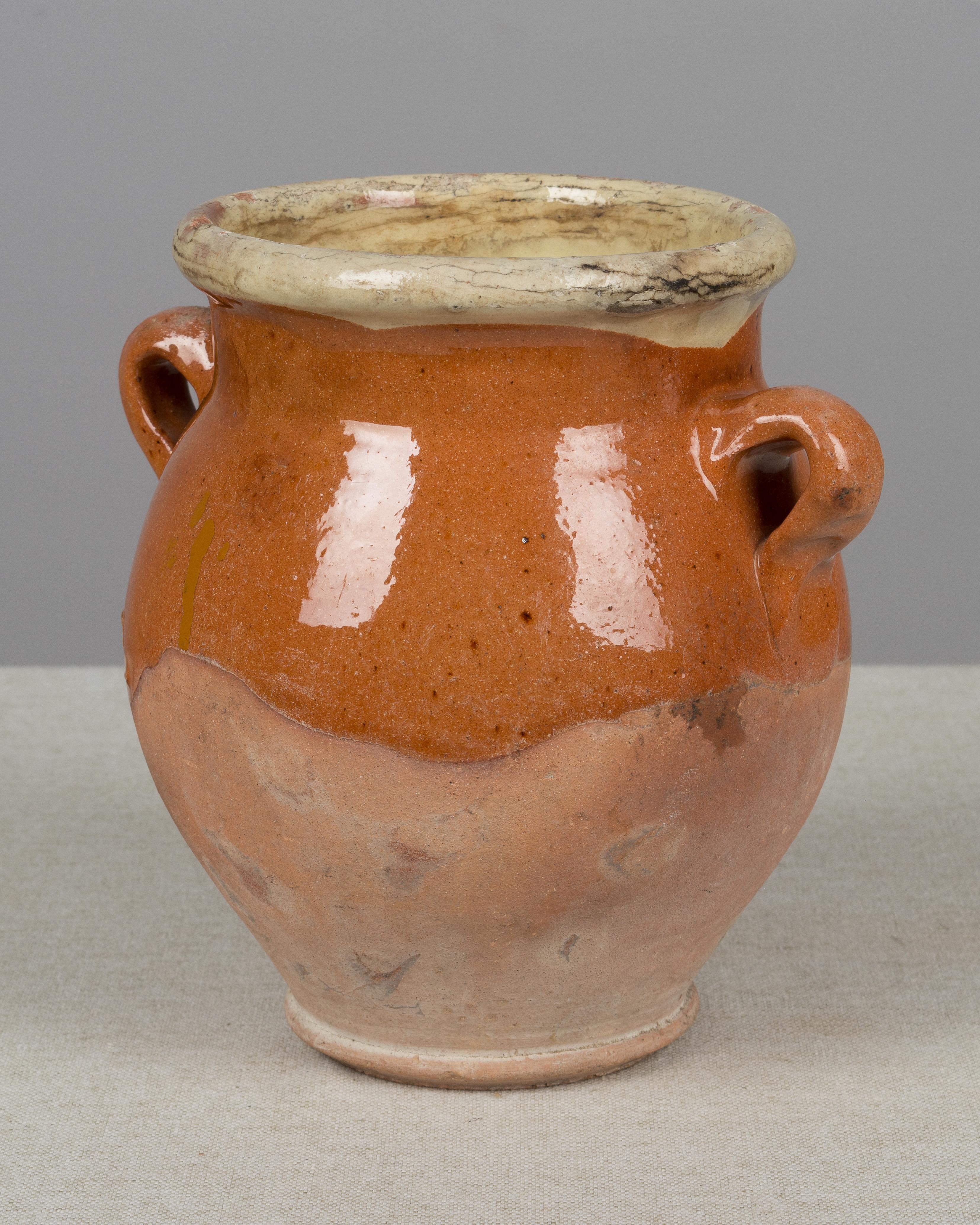 A small earthenware confit pot from the Southwest of France with traditional terracotta glaze. Beautiful patina. Minor losses. These ordinary earthenware vessels were once used daily in the French country home and have beautiful rustic glazes of