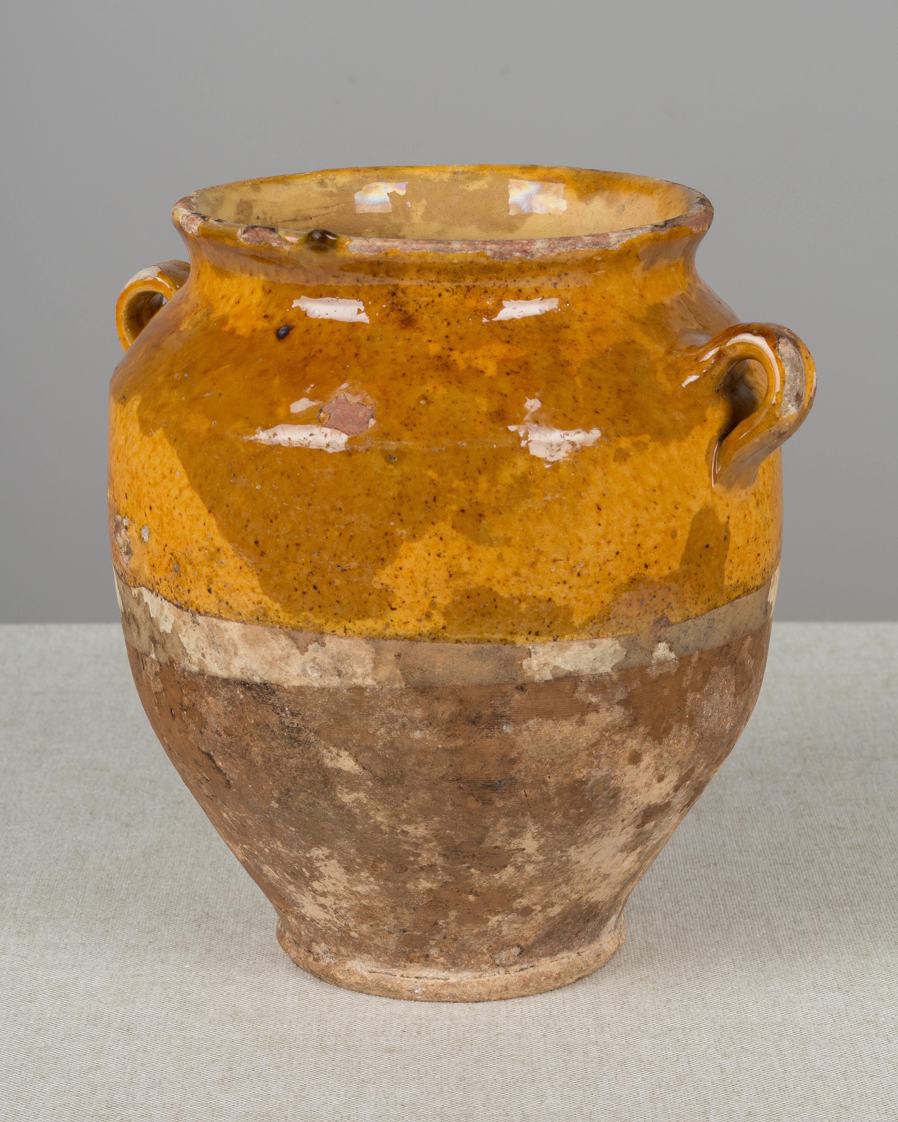 An earthenware confit pot from the Southwest of France with traditional ochre glaze. Beautiful patina and deep color. Some losses to glaze. These ordinary earthenware vessels were once used daily in the French country home and have beautiful rustic