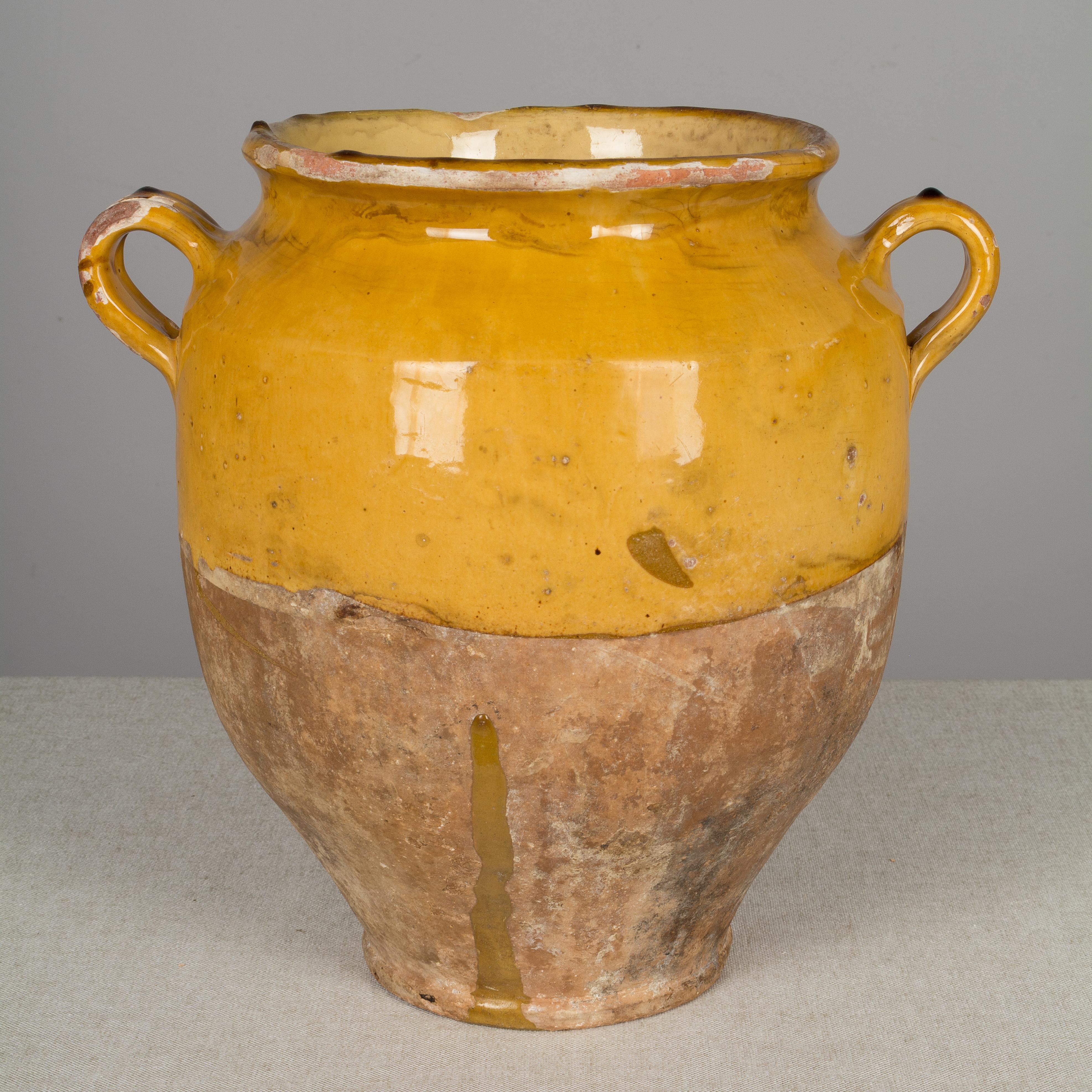 An earthenware confit pot from the Southwest of France with traditional yellow glaze. Beautiful patina and bright yellow color. Minor losses to glaze. Weight: 7.4 lbs. These ordinary earthenware vessels were once used daily in the French country