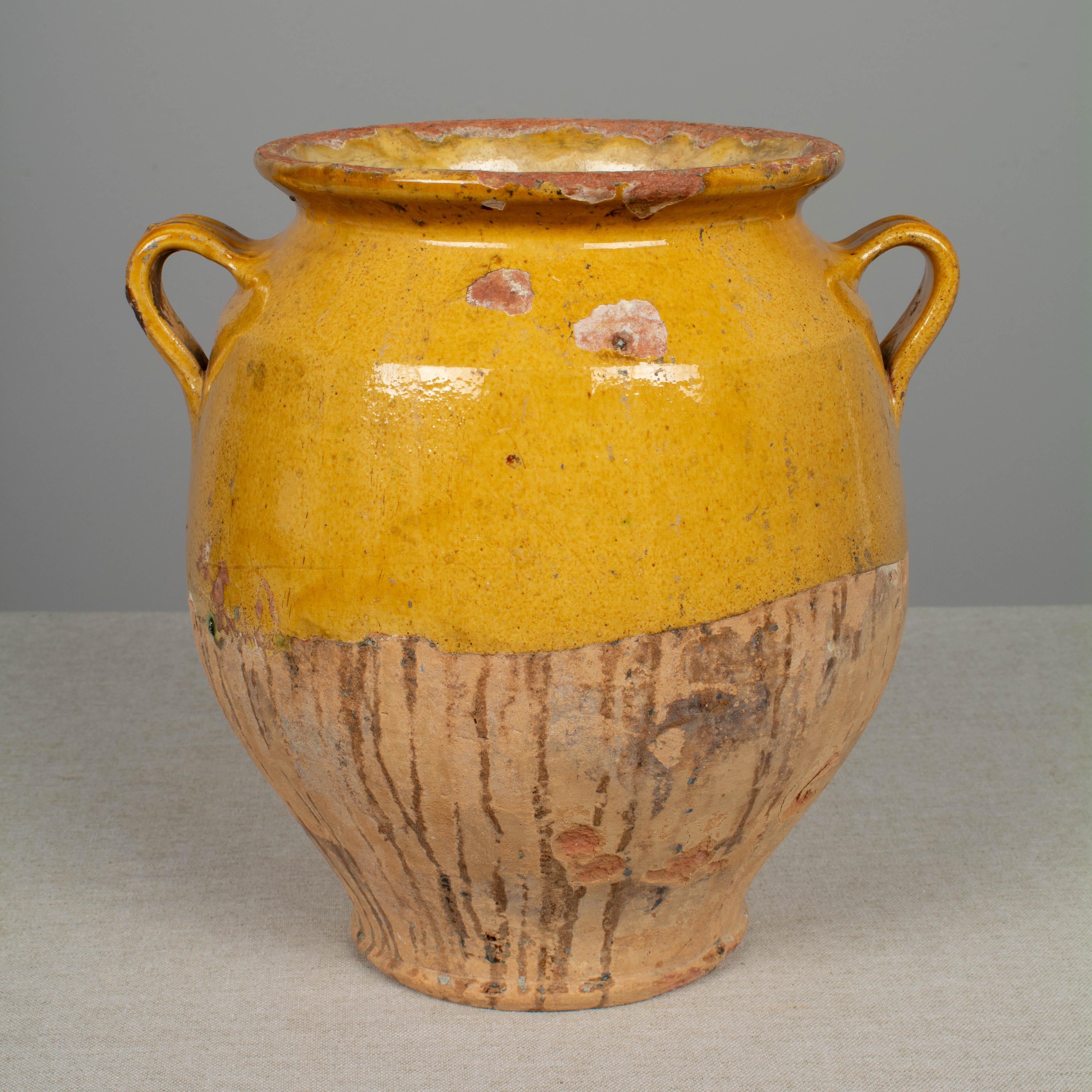 An earthenware confit pot from the Southwest of France with traditional yellow glaze. Beautiful patina and bright yellow color. Hairline cracks and losses to glaze. Weight: 5.8 lbs. These ordinary earthenware vessels were once used daily in the