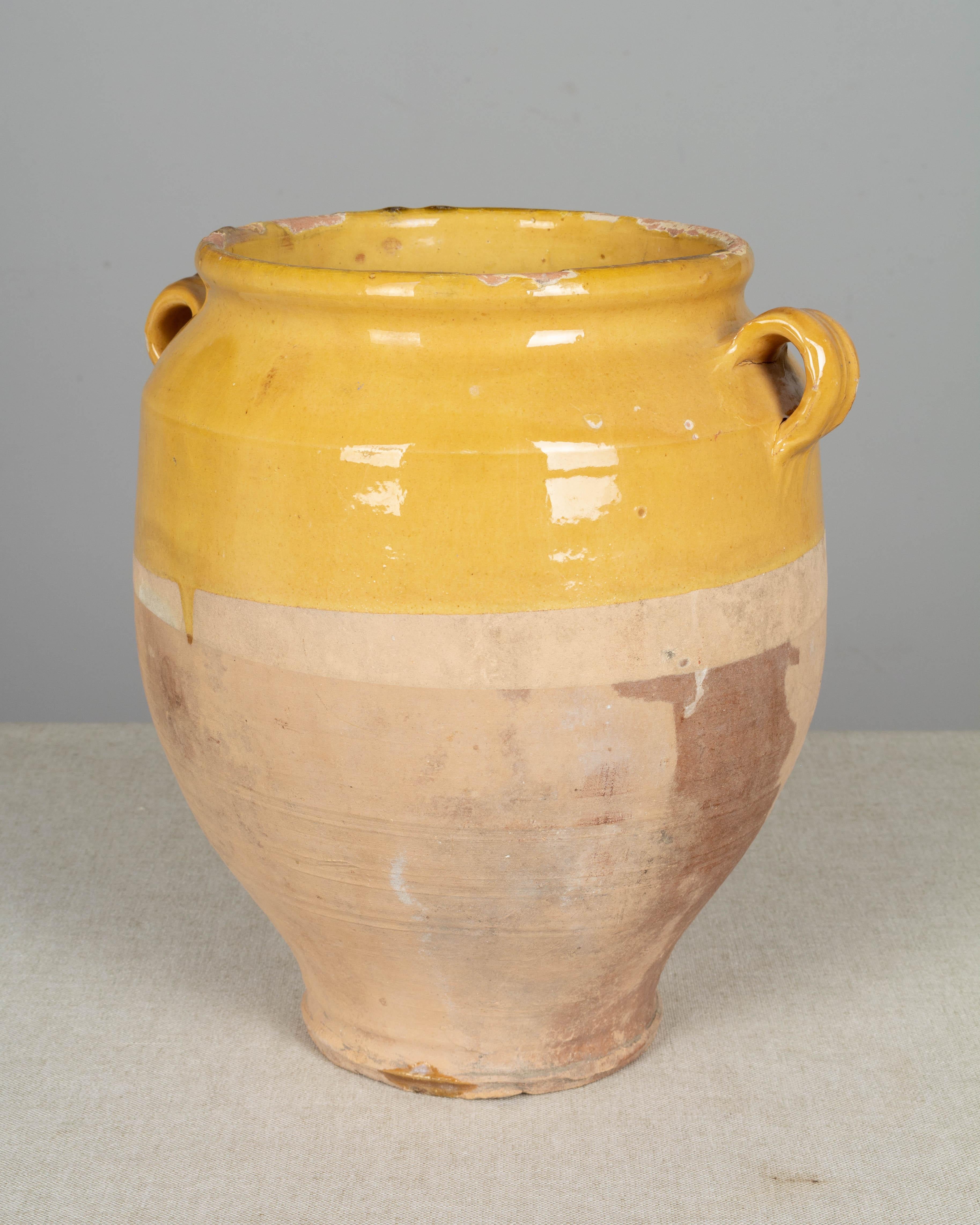An earthenware confit pot from the Southwest of France with traditional yellow glaze. Some chips and losses to glaze. These ordinary earthenware vessels were once used daily in the French country home and have beautiful rustic glazes of green, ochre