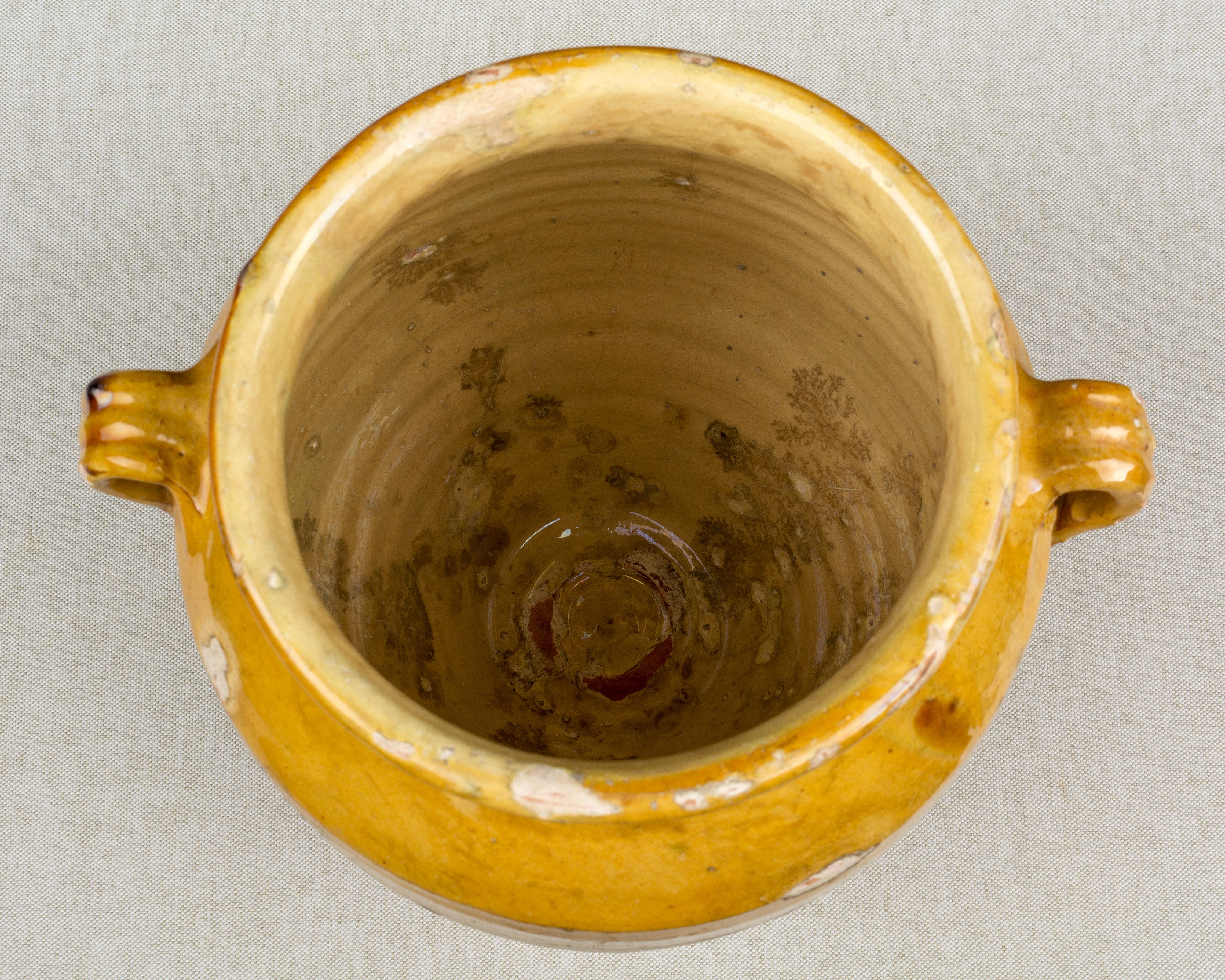 An earthenware confit pot from the Southwest of France with traditional ochre yellow glaze. Beautiful patina and bright yellow color. Minor losses to glaze. These ordinary earthenware vessels were once used daily in the French country home and have