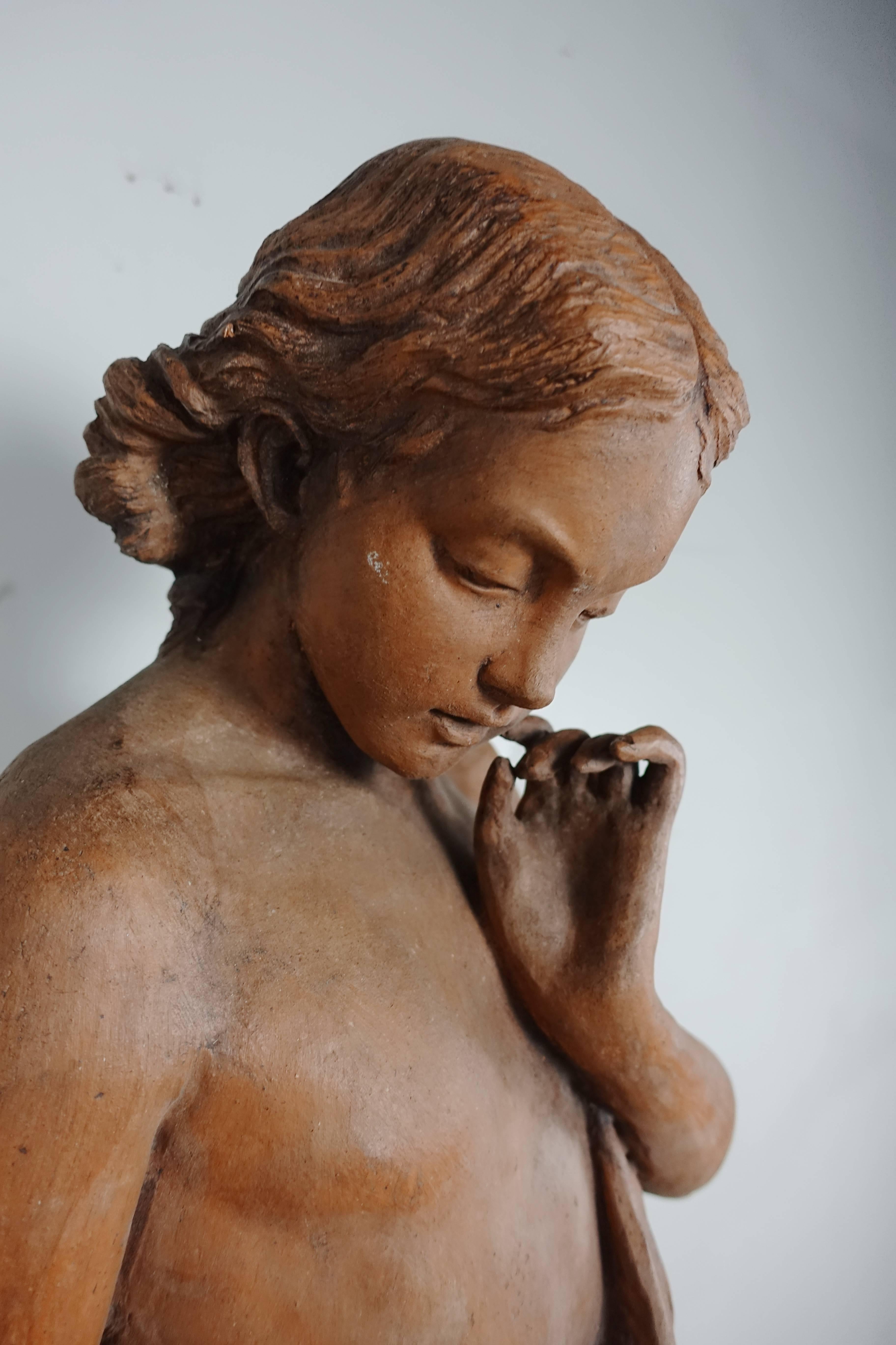 1930s French terracotta figure of a woman holding a flower. She is mounted on an iron base.