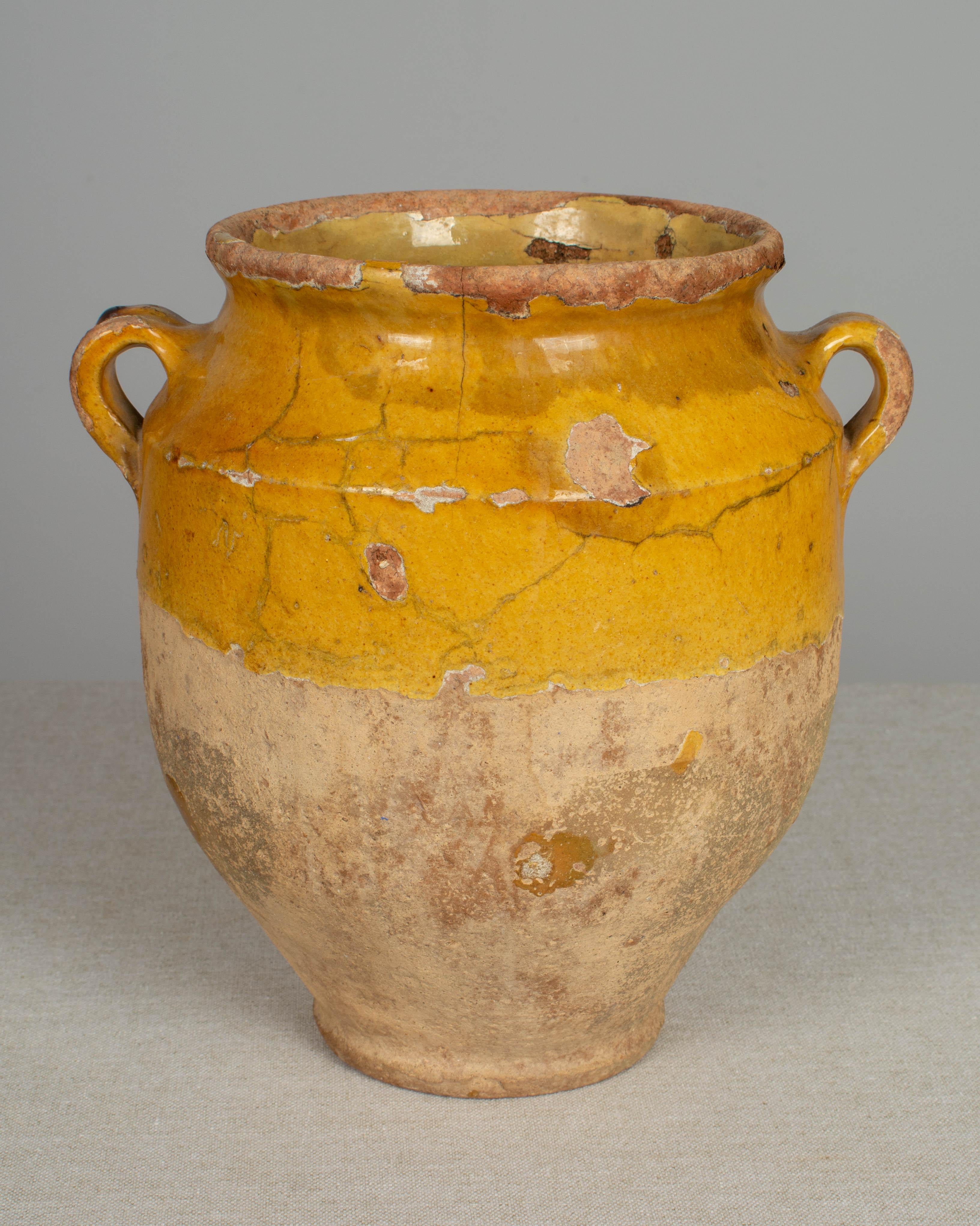 An earthenware confit pot from the Southwest of France with traditional yellow glaze. Beautiful patina and bright yellow color. Hairline cracks and losses to glaze. Weight: 4.2 lbs. These ordinary earthenware vessels were once used daily in the