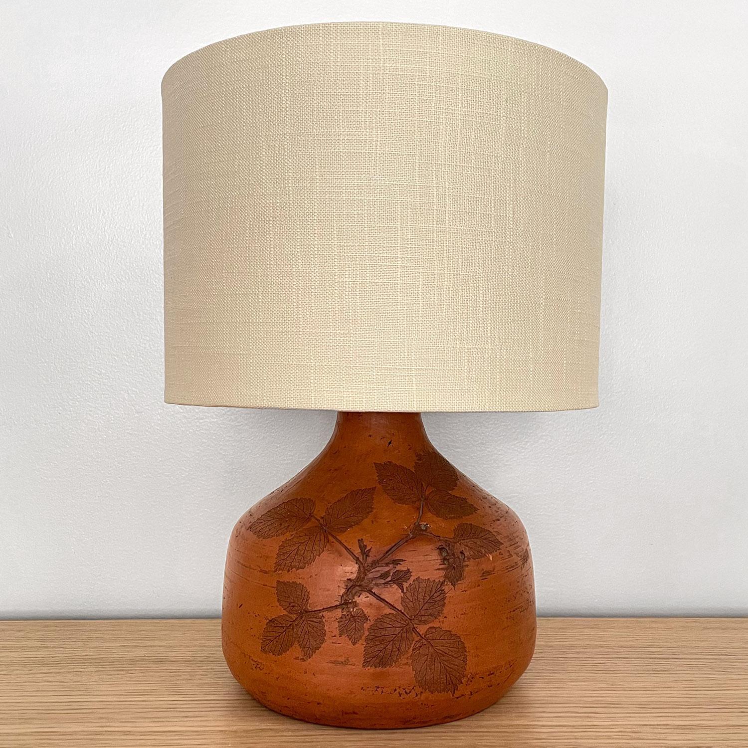 French terracotta table lamp
France, circa 1970s
Floral fossil imprints adorn the terracotta lamp base
Beautifully preserved moment in time
Patina from age and use
New linen shade with diffuser
Newly rewired
Single socket medium base.