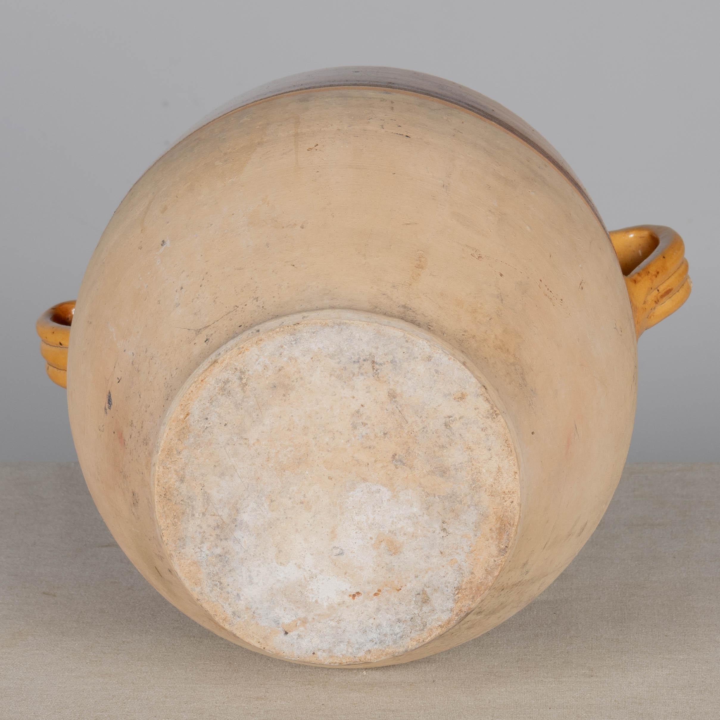 Olla de barro cocido del suroeste de Francia con vidriado tradicional amarillo ocre. Buen estado, con pequeñas pérdidas en el esmalte del borde. Estas vasijas de barro ordinario se utilizaban antaño a diario en las casas de campo francesas y