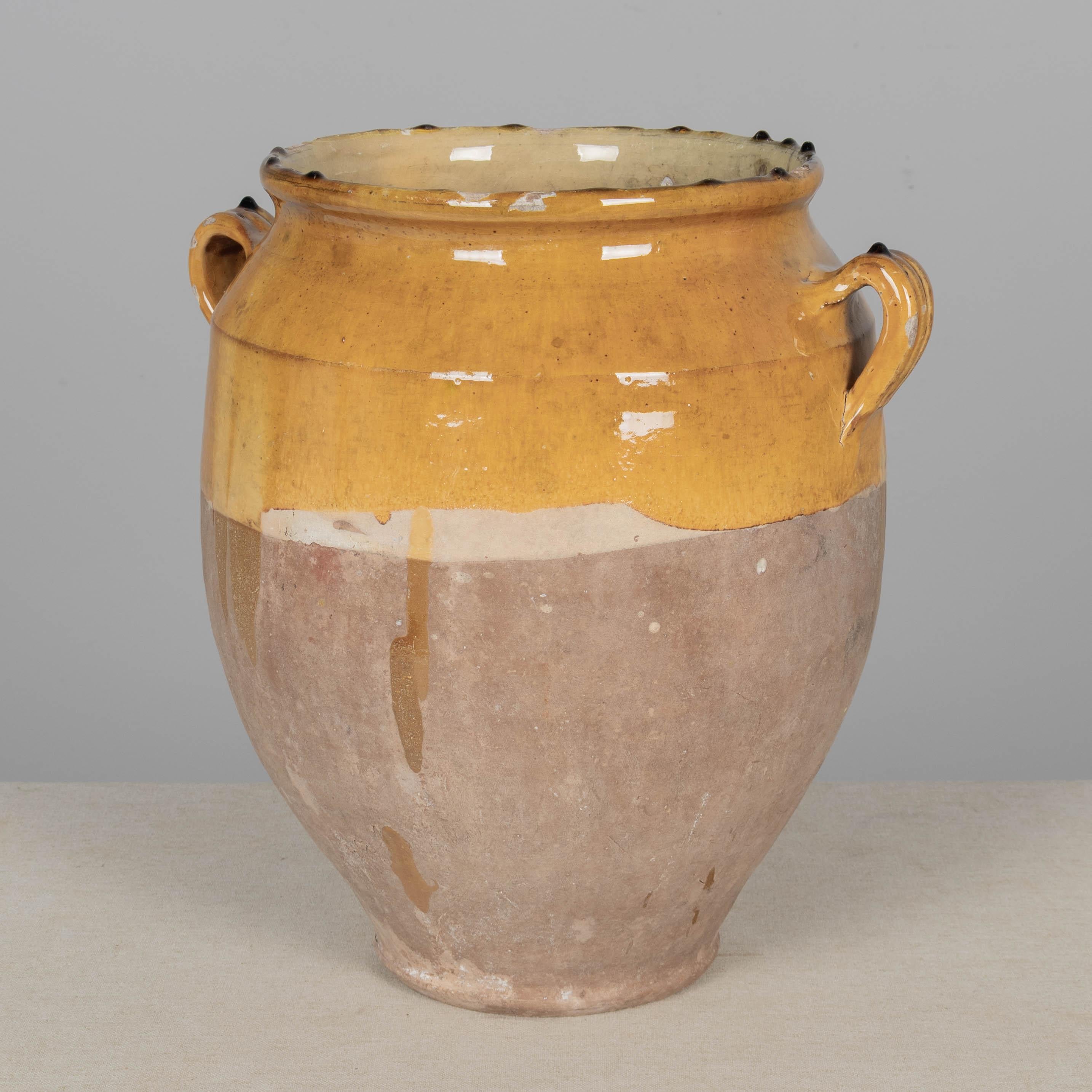 An earthenware confit pot from the Southwest of France with traditional yellow ochre glaze. Minor chips and losses to glaze, hairline crack near top. These ordinary earthenware vessels were once used daily in the French country home and have