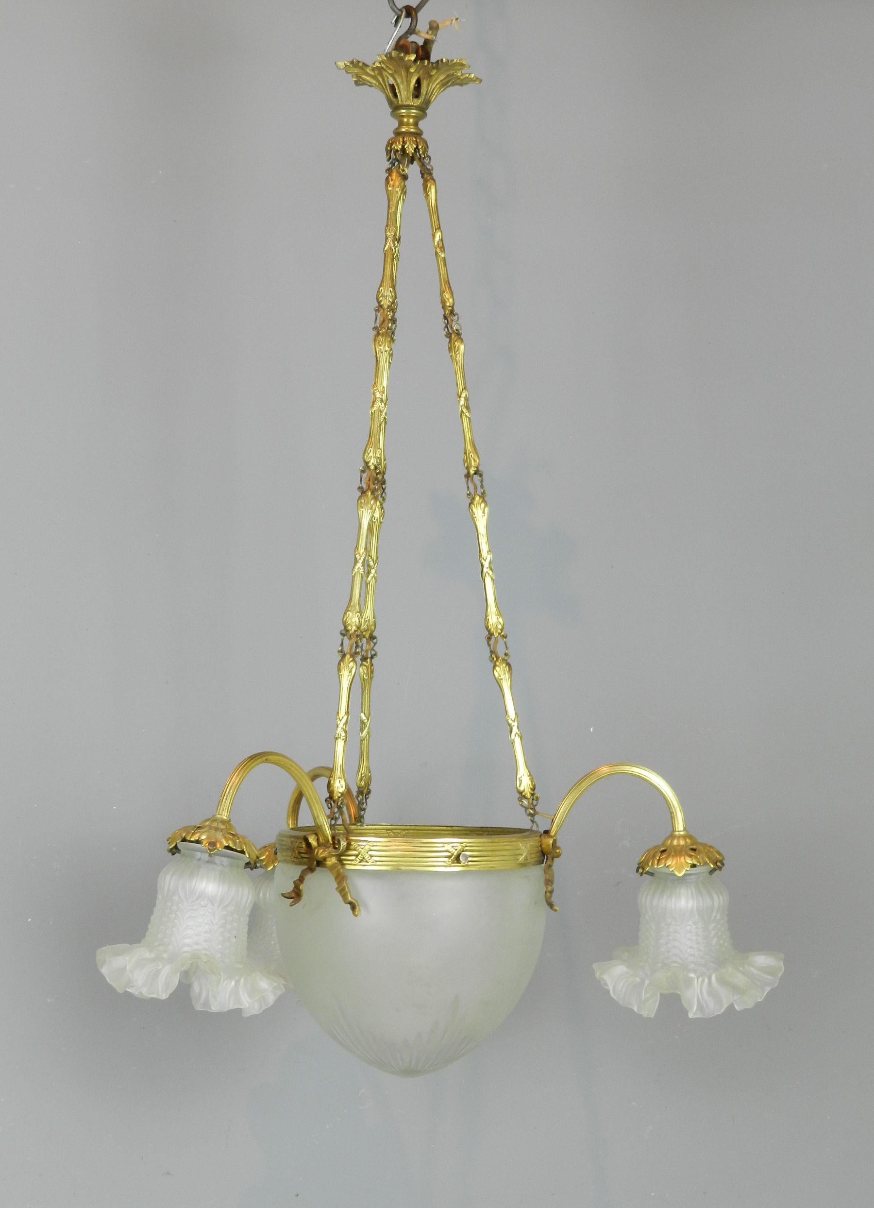 An impressive 1930s French three arm ceiling light with a frosted and cut glass bowl held within a brass retaining ring decorated with bows.

Issuing from the ring are three reeded foliate tulip holders. This all hangs from three decorative brass