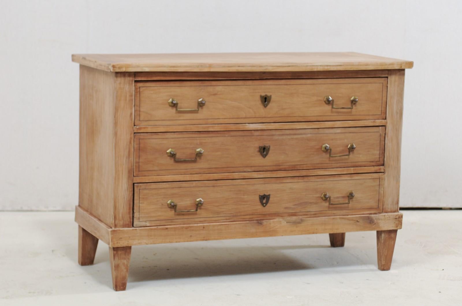 A French three-drawer chest of drawers from the 19th century. This antique commode from France has a clean, simple design with a slightly overhanging top which rests above a cabinet housing three full-sized, graduated, dove-tailed drawers, and is