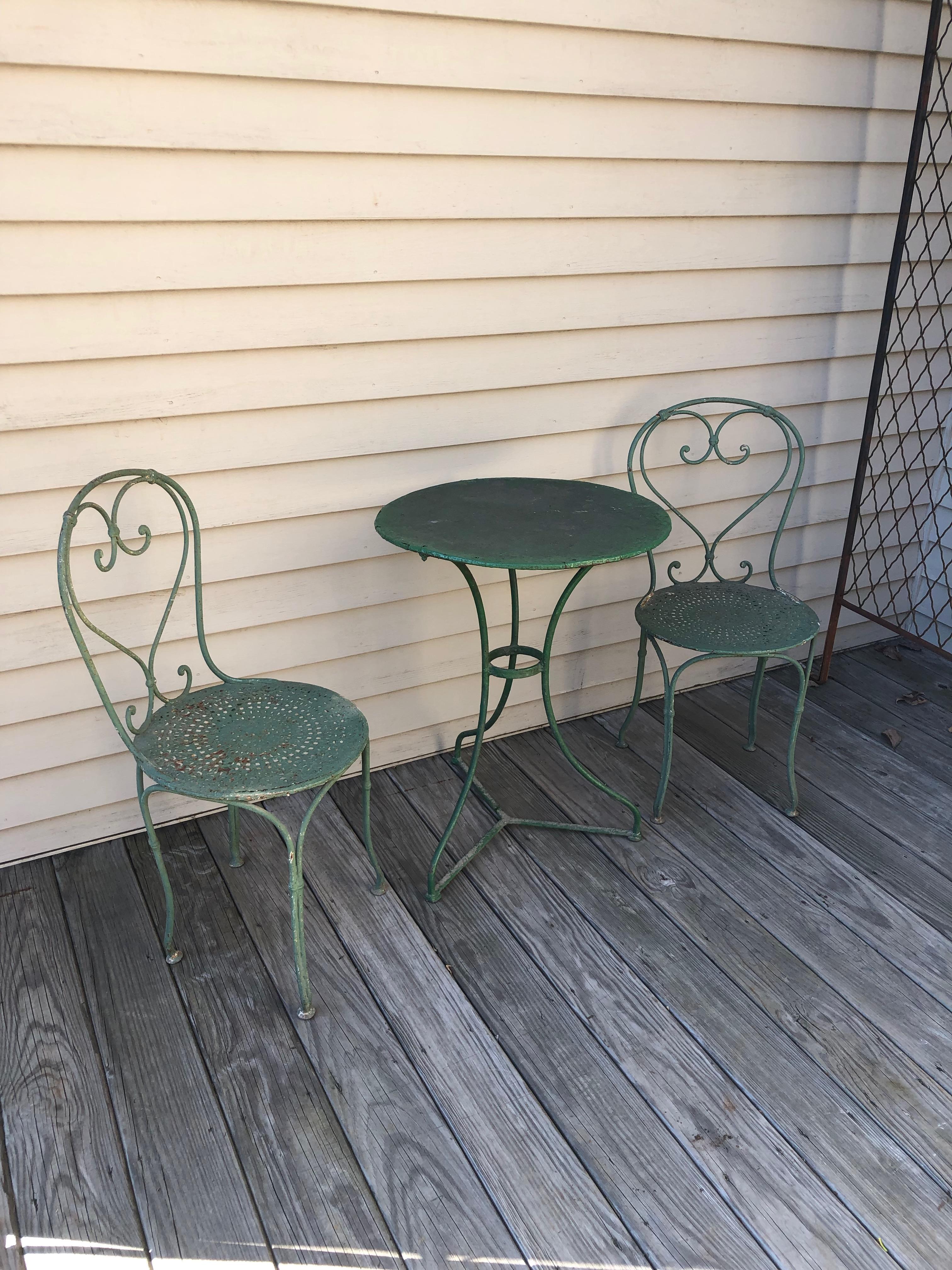 Oh, to sit in the shade, underneath a tree, with a drink in hand, planning your next holiday. That’s what this lovely three-piece bistro set in old green paint was made for! The chairs have beautiful pierced seats, heart-motif backs, and date to