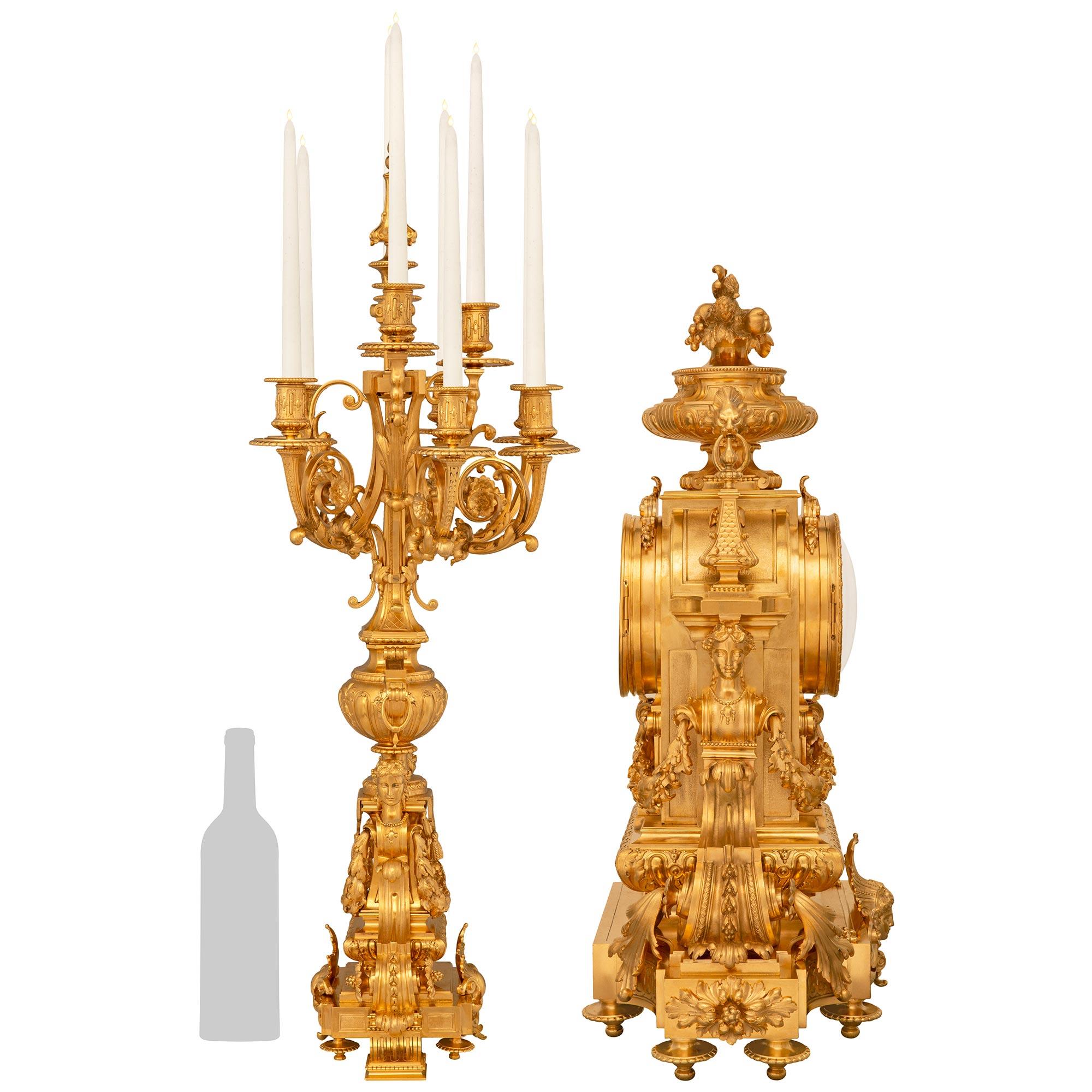 An extremely detailed and high quality French 19th century Regence st. Ormolu three piece garniture set, signed by the Lemerle-Charpentier foundry. This monumental garniture set consists of two candelabras and one clock. The clock is raised on a