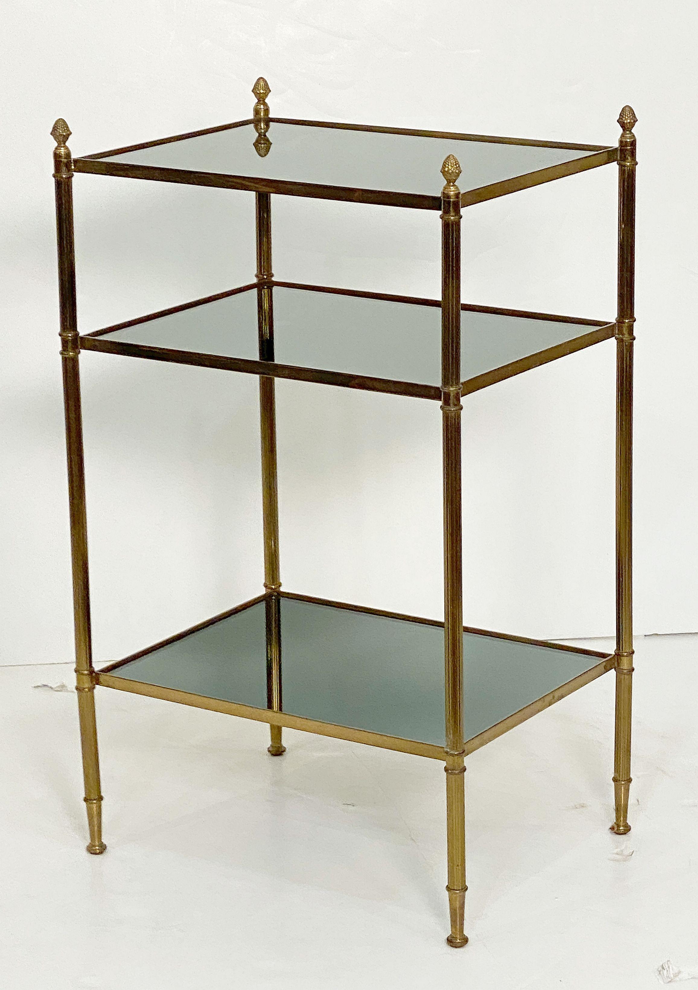 A fine French Mid-Century Modern rectangular side or end table, featuring three tiers of tinted mirrored glass and a stretcher frame of brass with tapering legs and finials.