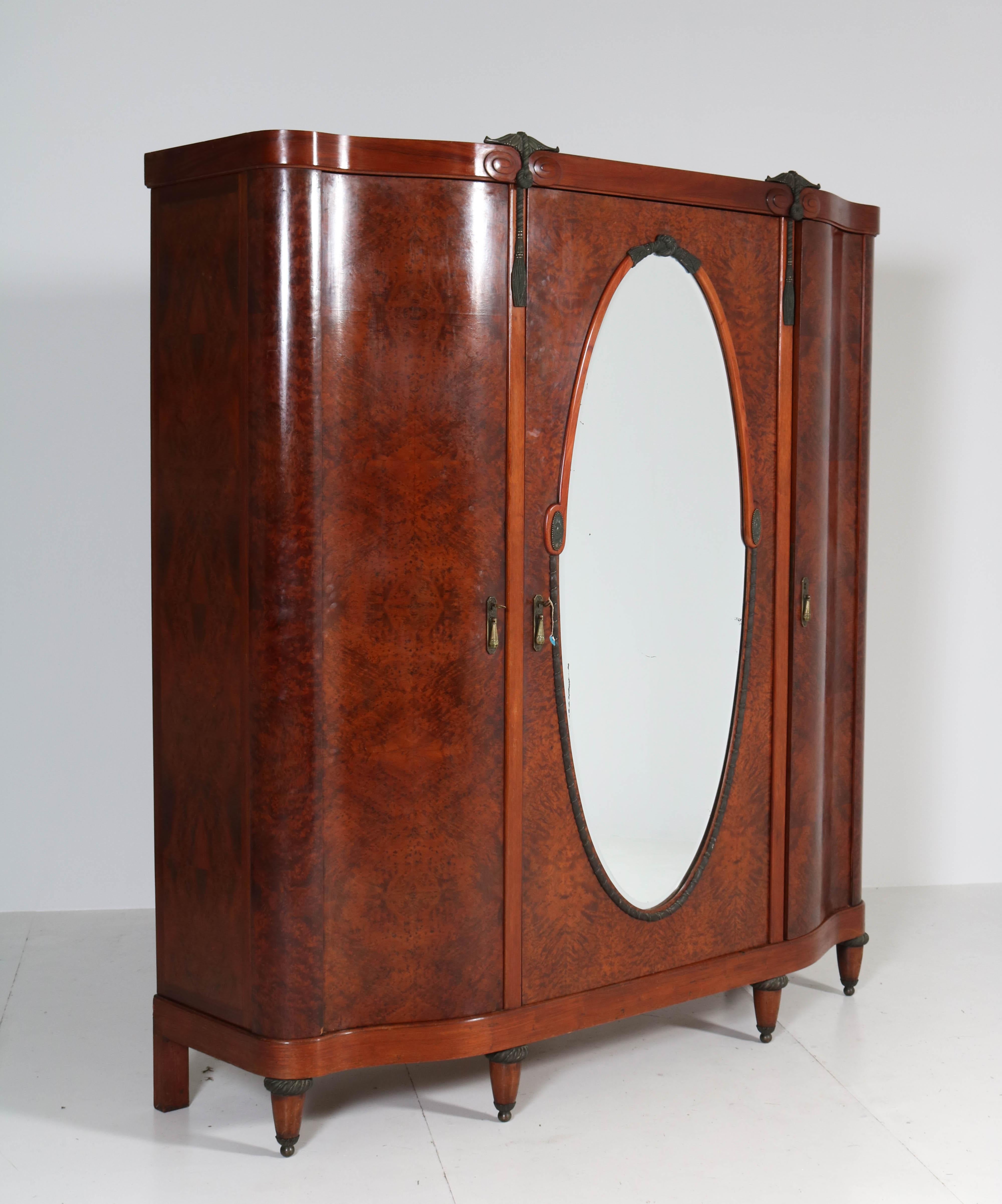 Stunning and rare Art Deco wardrobe or armoire.
Striking French design from the thirties.
Thuya burl with original bronze handles and ornaments.
Behind the door with the original beveled mirror is a brass bar for hanging clothes.
Eight wooden