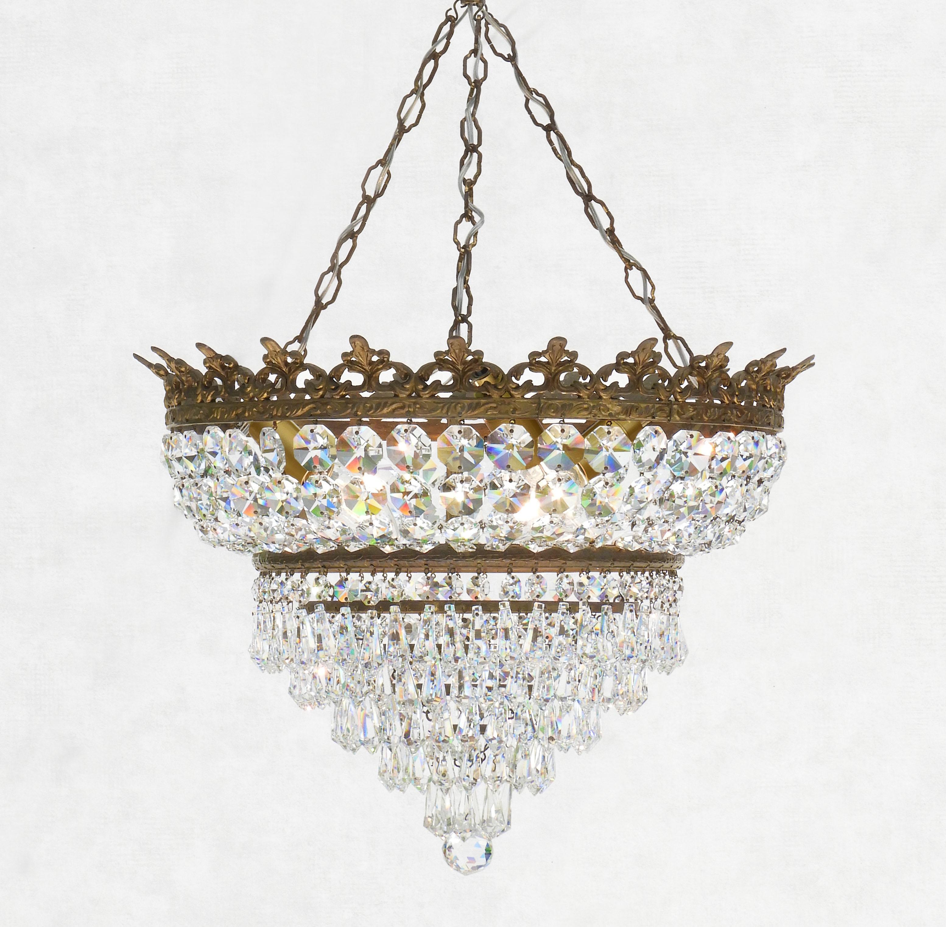 Magnifique lustre en cristal à couronne étagée, datant des années 1930 en France.  Une myriade d'objets octogonaux aux multiples facettes 
et des pampilles en cristal, suspendues à la couronne de bronze et terminées par un globe en cristal taillé à