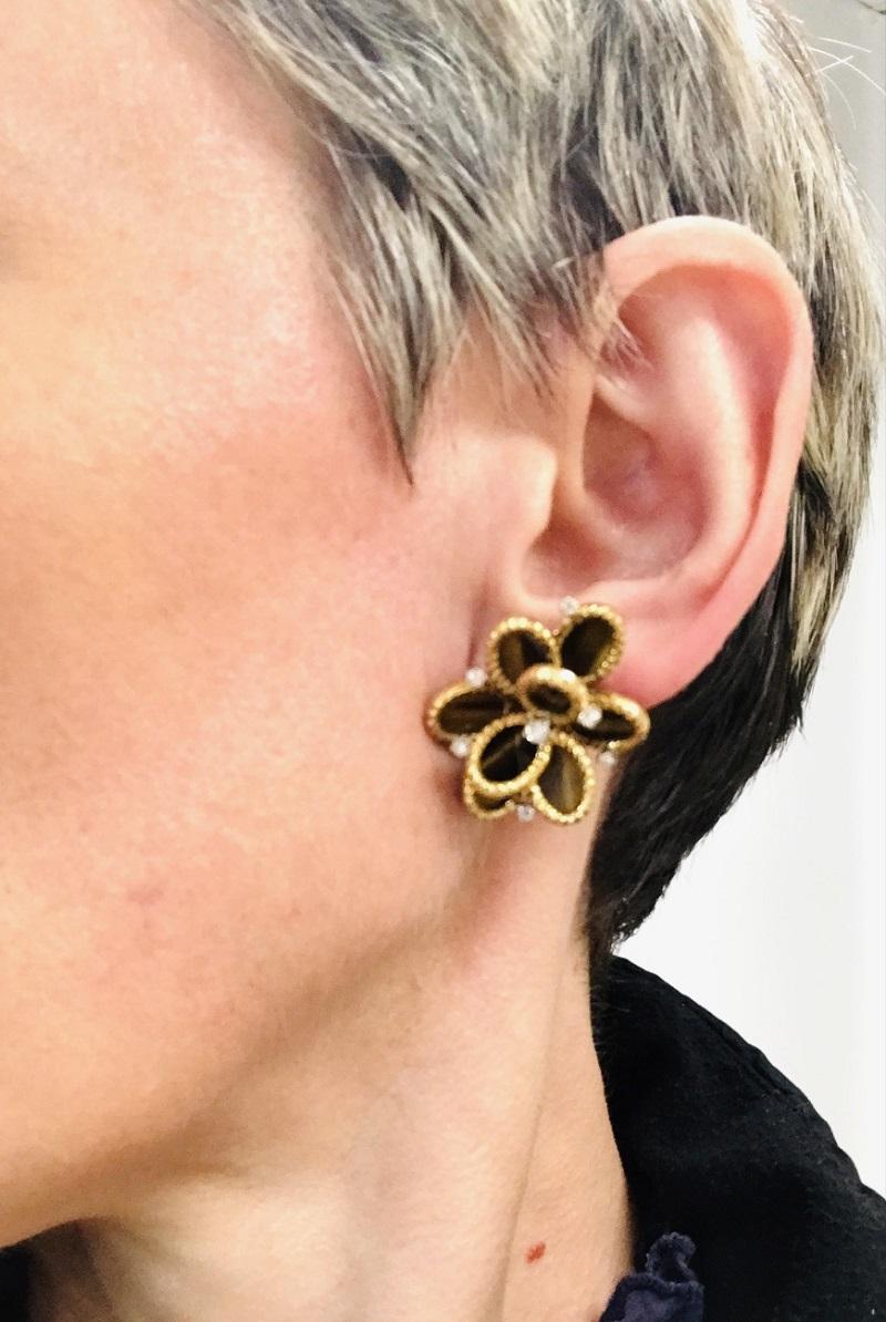 A pair of French tiger's eye earrings, made of 18k gold with tiger’s eye gemstones and diamonds. 
This vintage pair of French earrings offers a rich, earthy palette and a layered floral design. Each earring features eight oval sliced tiger’s eyes