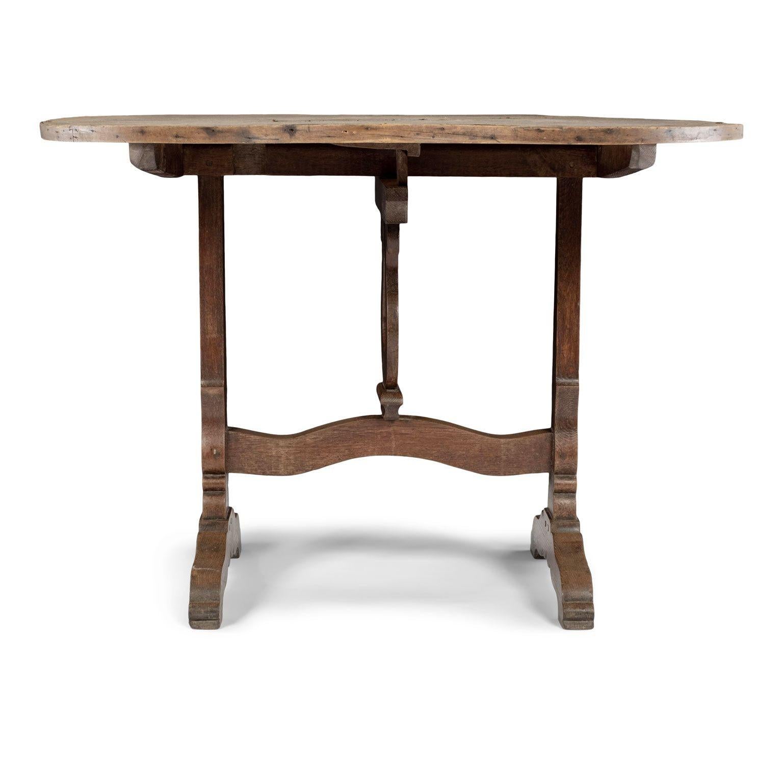 French tilt-top 'table de vendange,' or wine-tasting table circa 1870-1910. Large round top, covered in original canvas, circled by bentwood edge. Oak carved trestle base with lyre-shape harp mechanism. All hand-carved. Naturally semi-bleached