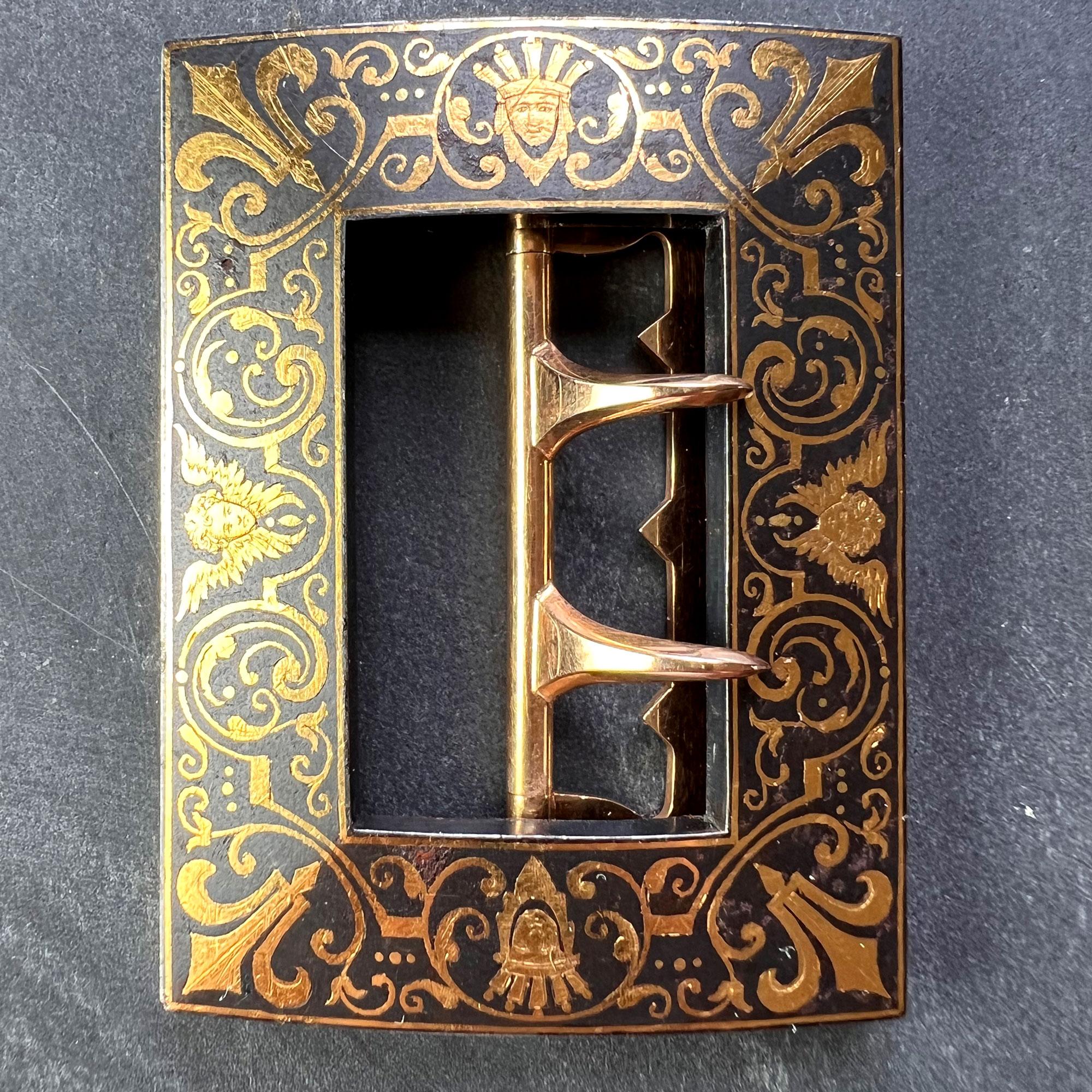 A blackened steel and 18 karat (18K) yellow gold Damascene belt buckle designed as a rectangle with inlaid gold designs of angels and geometric lines in the style of Boucheron. Stamped with the owl for 18K gold and French import to the buckle claws