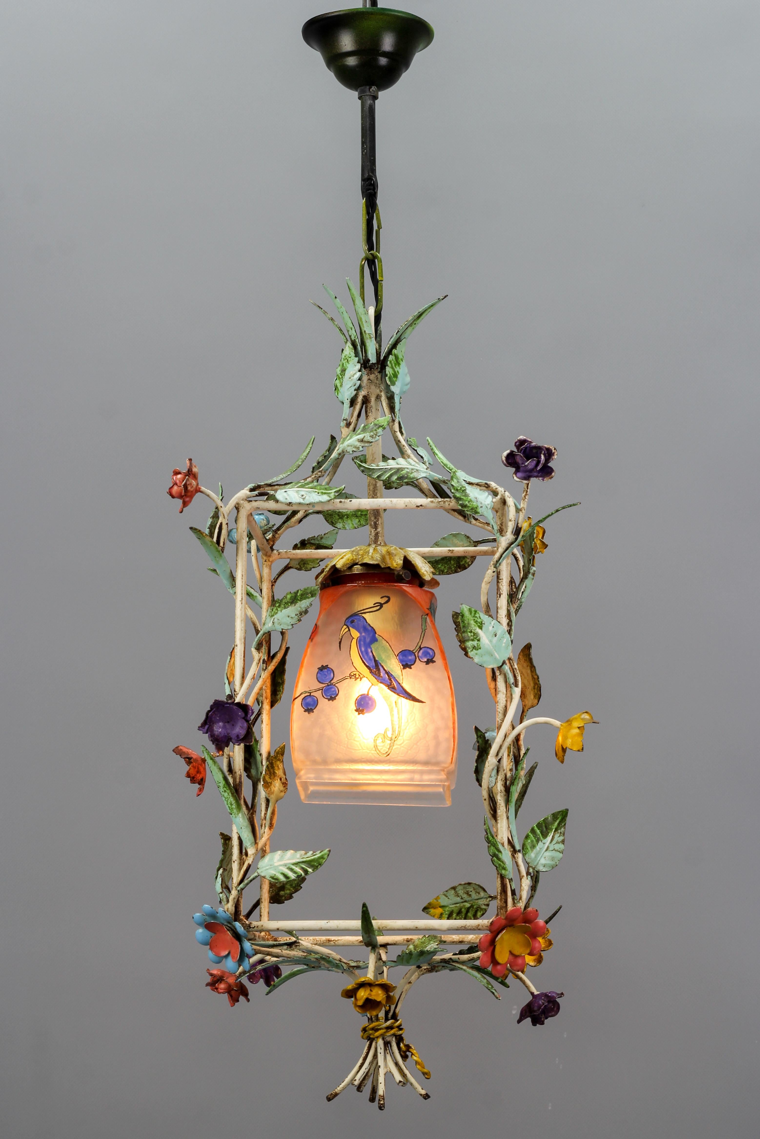 French Tole and glass polychrome pastel flower cage pendant light, circa the 1950s.
Adorable cage-shaped pendant light fixture made of hand-painted metal in polychrome pastel tones, adorned with flowers and leaves. Single light with a frosted,