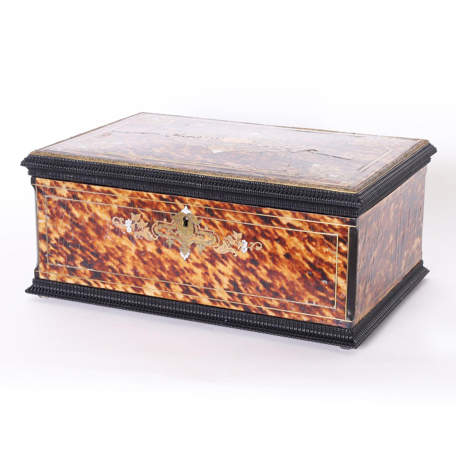 Impressive 19th century French lidded box handcrafted in hardwood clad in tortoise shell and decorated with copper, brass, and metal floral and geometric inlays. The interior is lined with alluring deep blue felt.