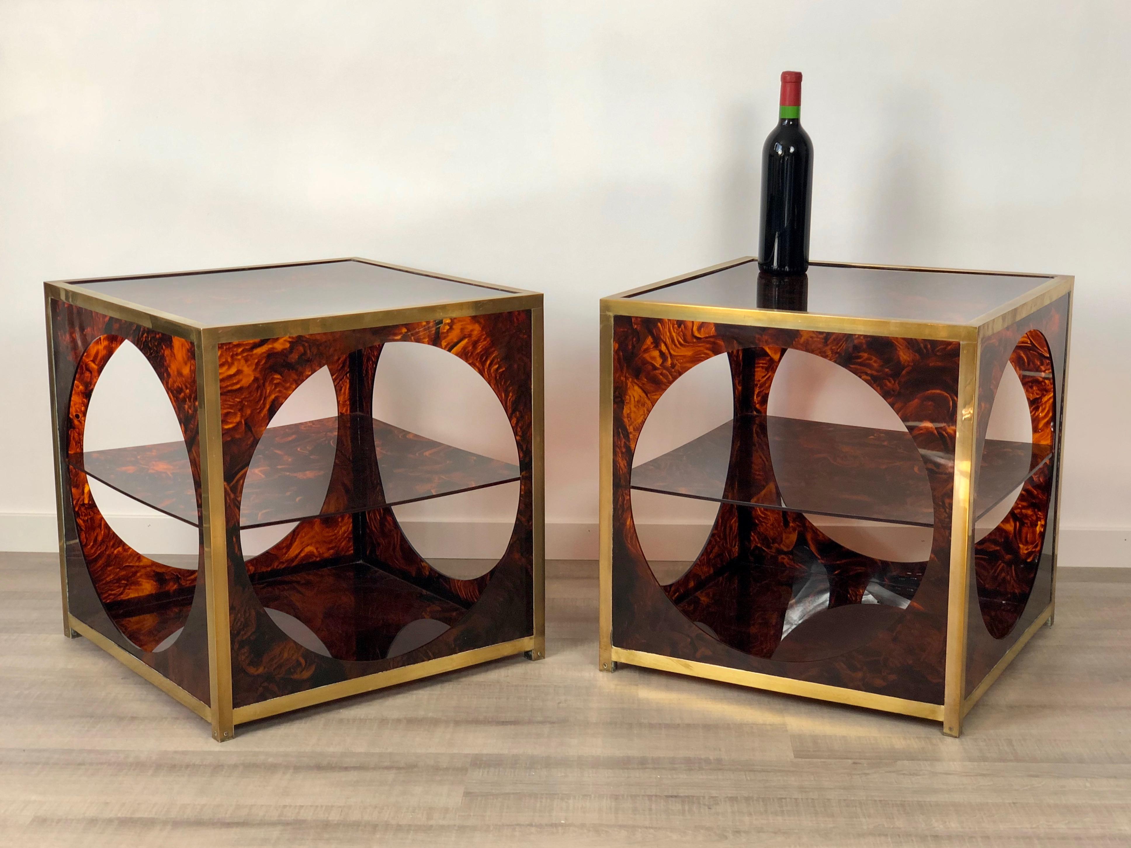 Pair of elegant side/coffee tables in faux tortoiseshell lucite and brass details. They feature an unique geometrical design that remembers 1970s' Christian Dior style: an open cube with circular windows inside which a Lucite shelf is