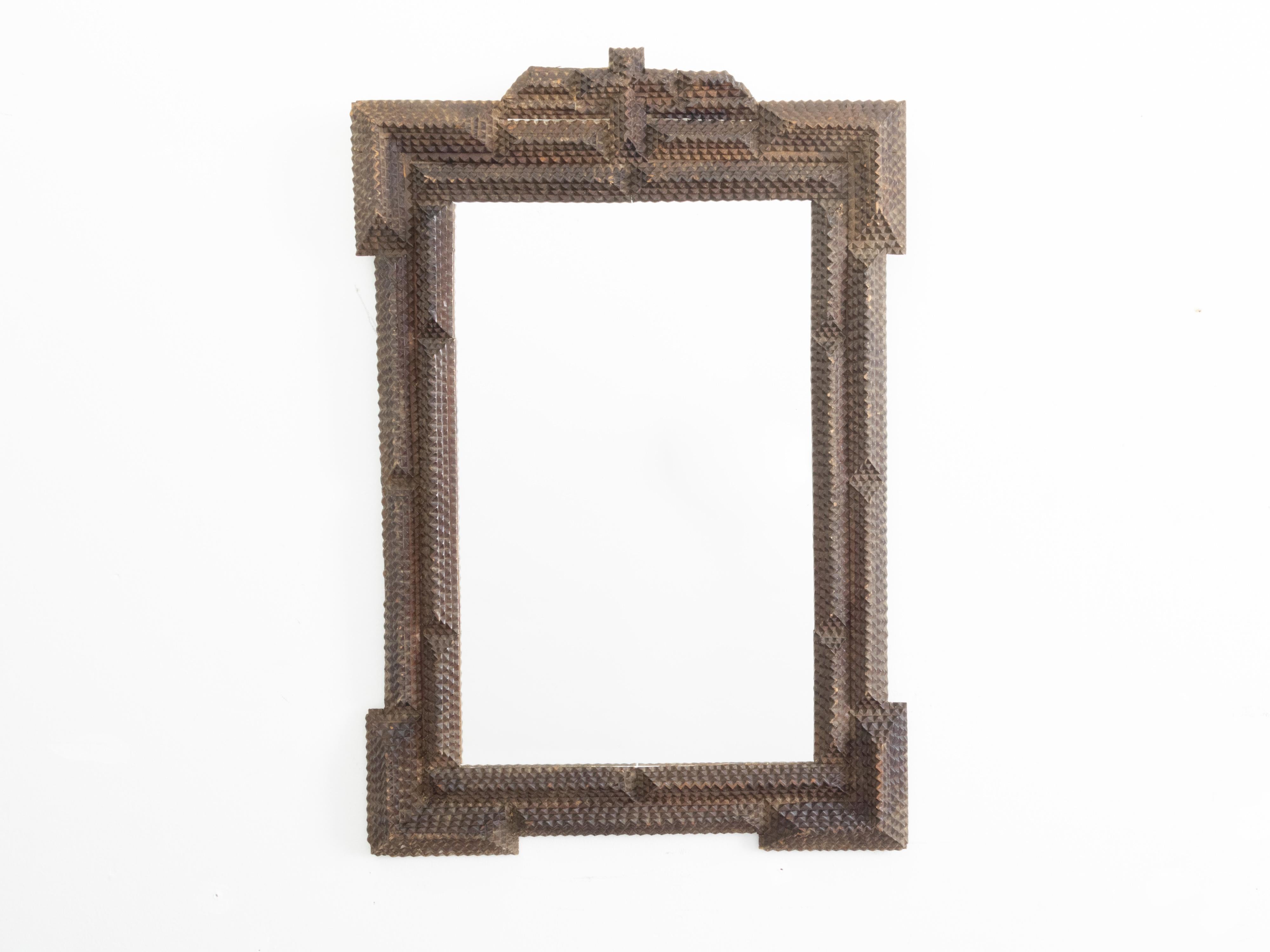A French Tramp Art hand carved mirror from the early 20th century, with raised motifs. Created in France during the Turn of the Century, this wooden mirror presents the stylistic characteristics typical of the Tramp Art style. A simple, linear