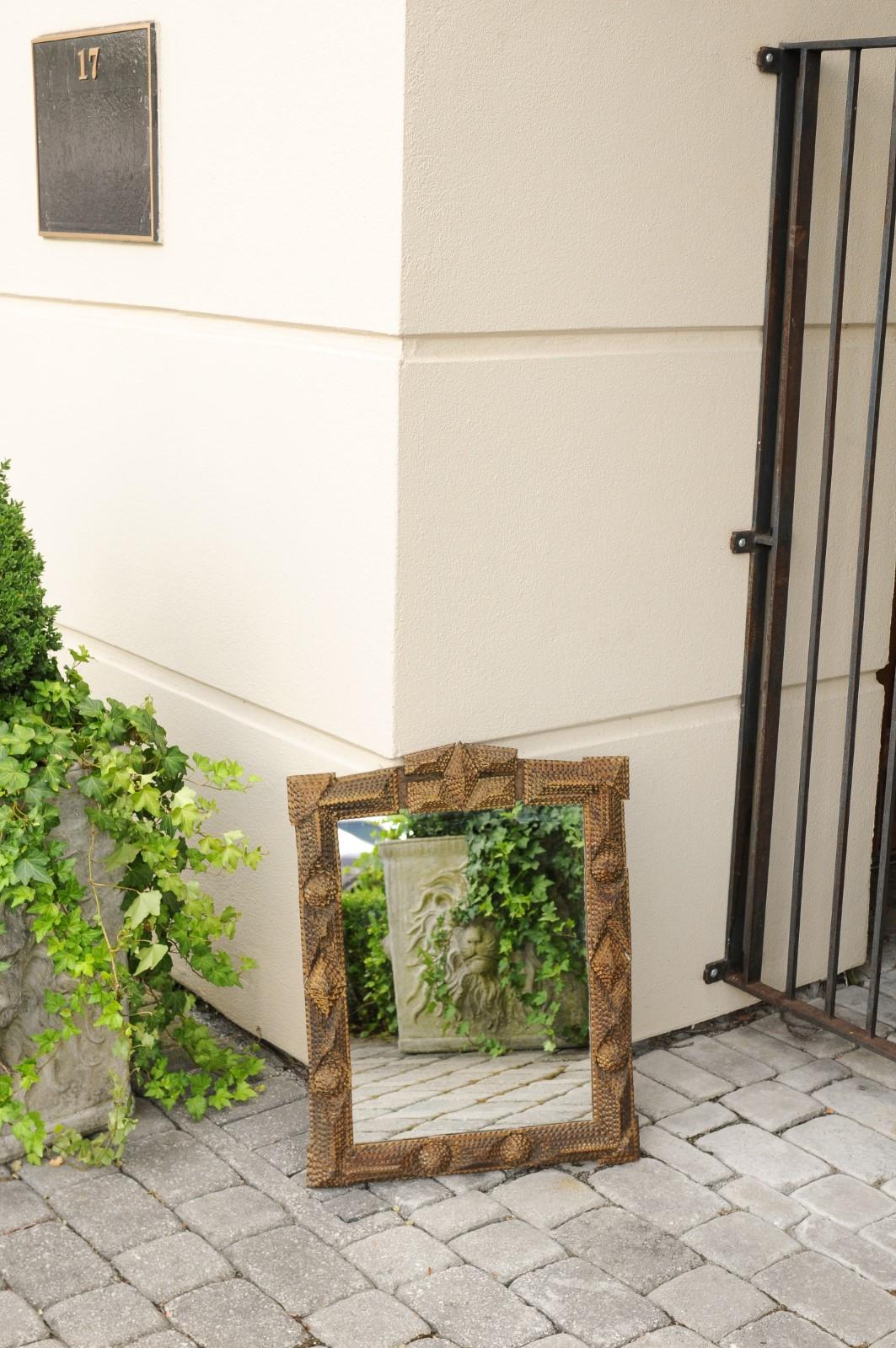 A French Tramp Art hand carved rectangular mirror from the early 20th century, with raised motifs and carved crest. Born in France during the transition of the 19th-20th century, this charming wooden mirror presents the stylistic characteristics