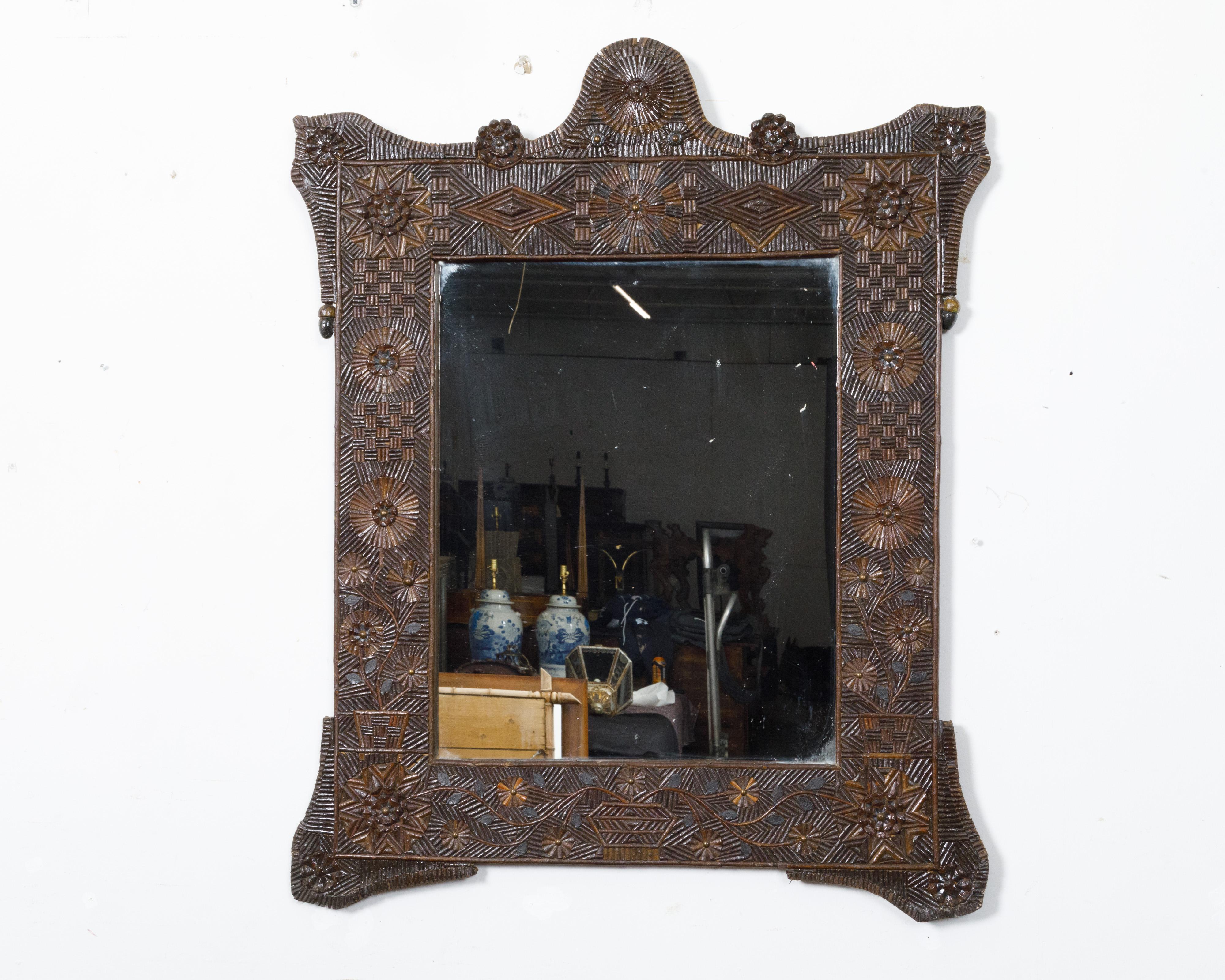 A French Tramp Art Turn of the Century wall mirror from circa 1900 with hand-carved geometric and floral décor. Hand-crafted in France around the turn of the century circa 1900, this exquisite wall mirror is a striking example of Tramp Art