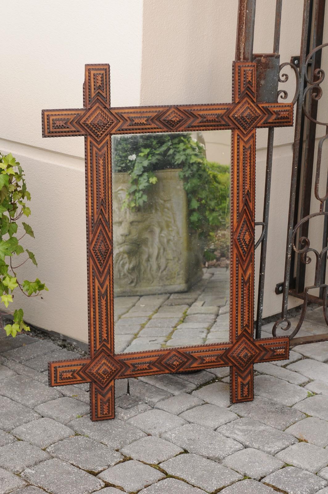 A French Tramp Art mirror from the turn of the century with alternating diamond motifs and contrasting colors . Born in the early years of the 20th century, this French mirror was hand carved in the manner typical of the Tramp Art style. Consisting