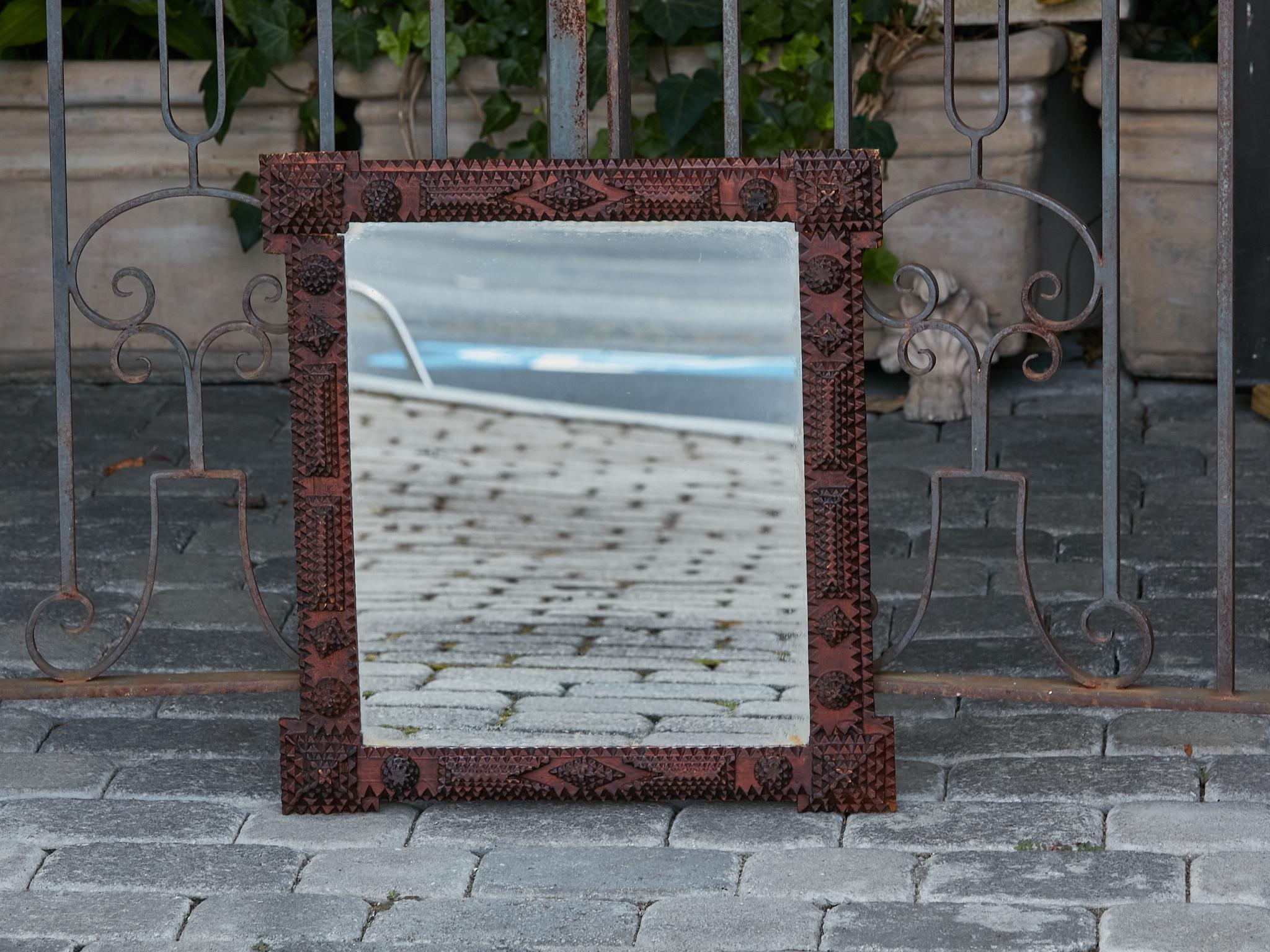 A French Tramp Art Turn of the Century mirror from circa 1900, with hand-carved geometric motifs and protruding corners. Delve into the captivating world of French Tramp Art with this Turn of the Century mirror from circa 1900, a piece that
