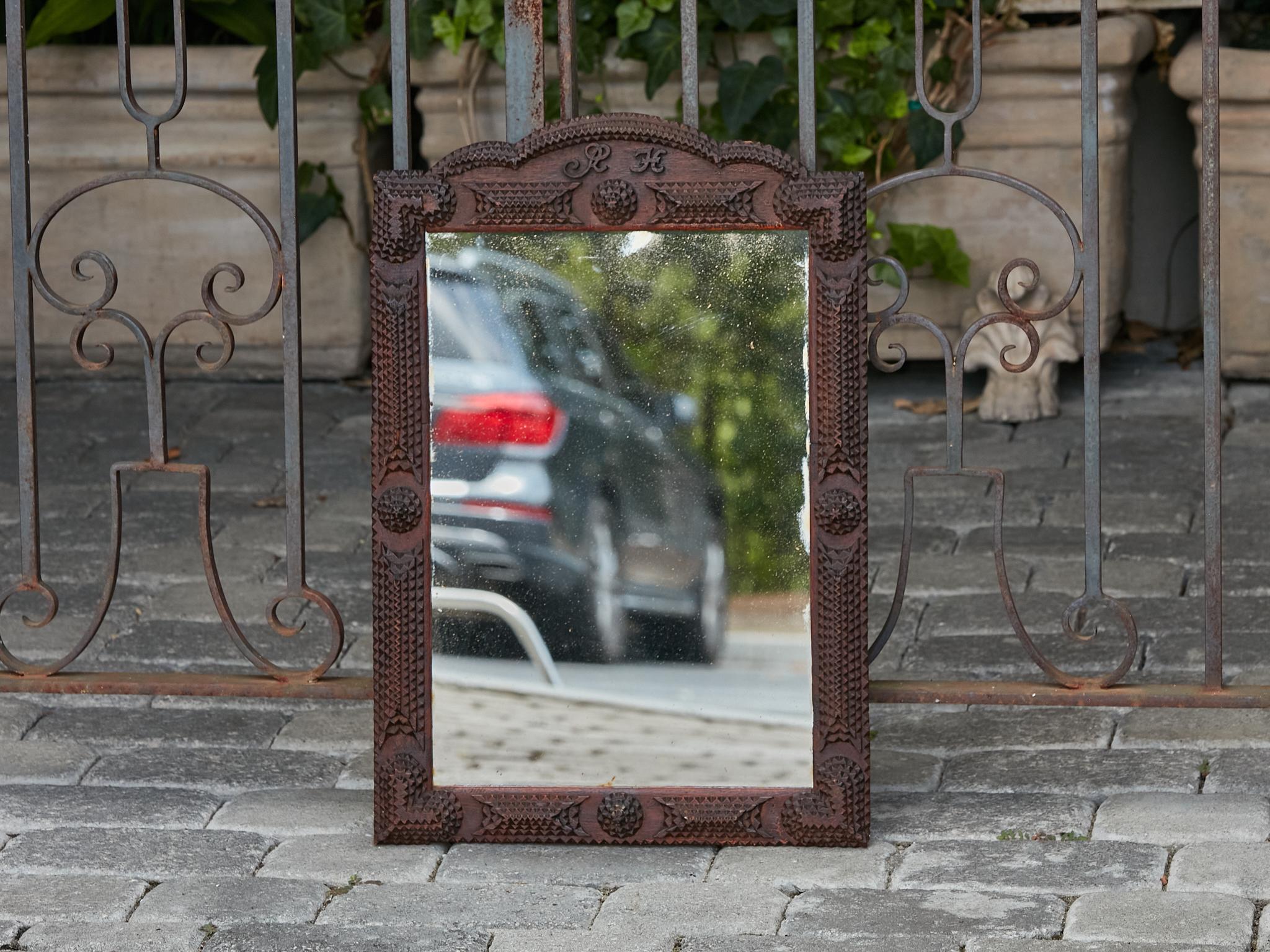 A French Tramp Art Turn of the Century mirror from circa 1900 with hand-carved crest and monogram. 
Immerse yourself in the exquisite craftsmanship and unique charm of this French Tramp Art Turn of the Century mirror from circa 1900. This