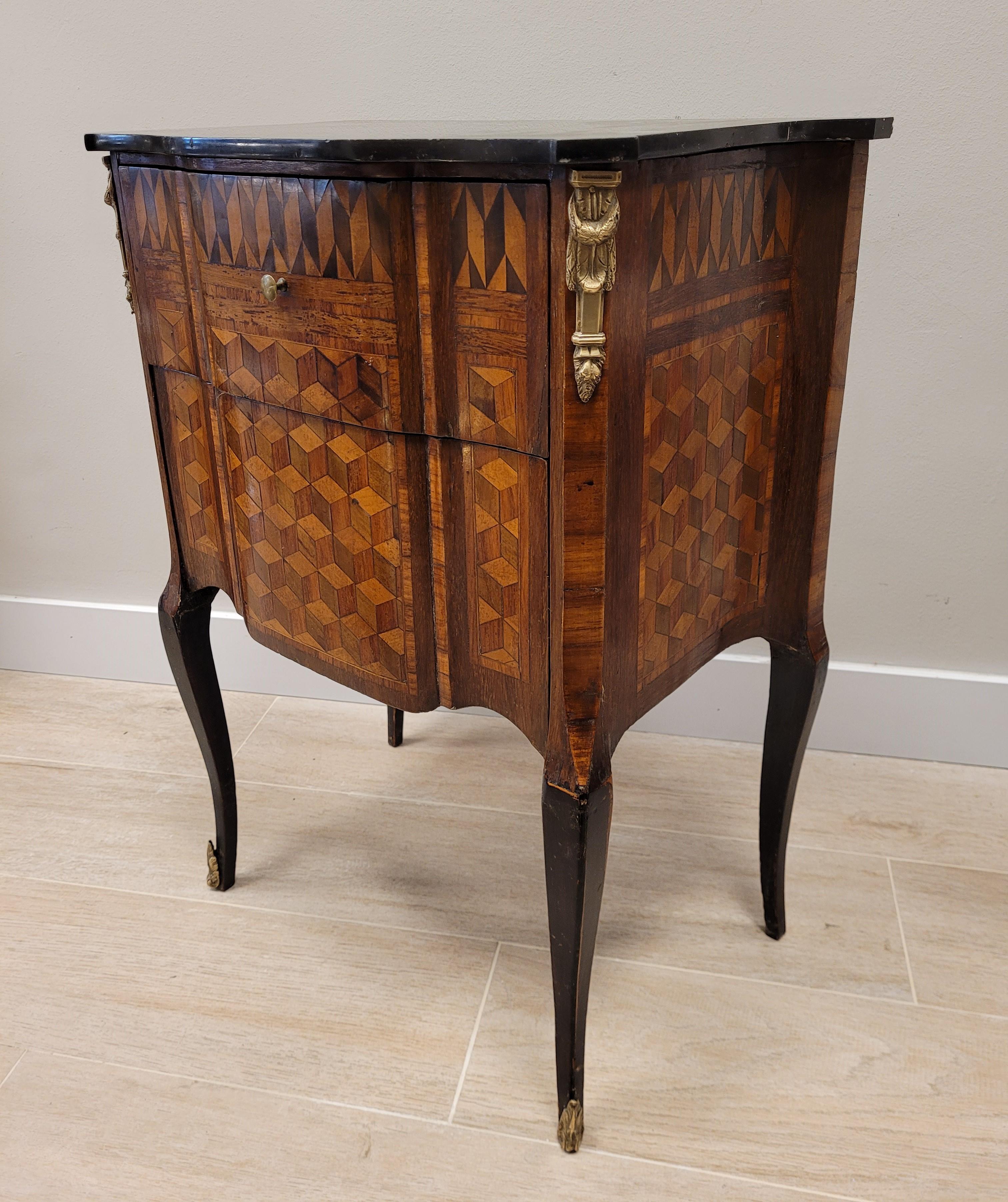 Amazing small French commode in wood with geometric and lozenges inlaid , bronze trim.The inlaid is an extraordinary and very refined work of art Craft work
With a mixtilinear profile and galveate legs, with bronze sabots on the front legs. It comes