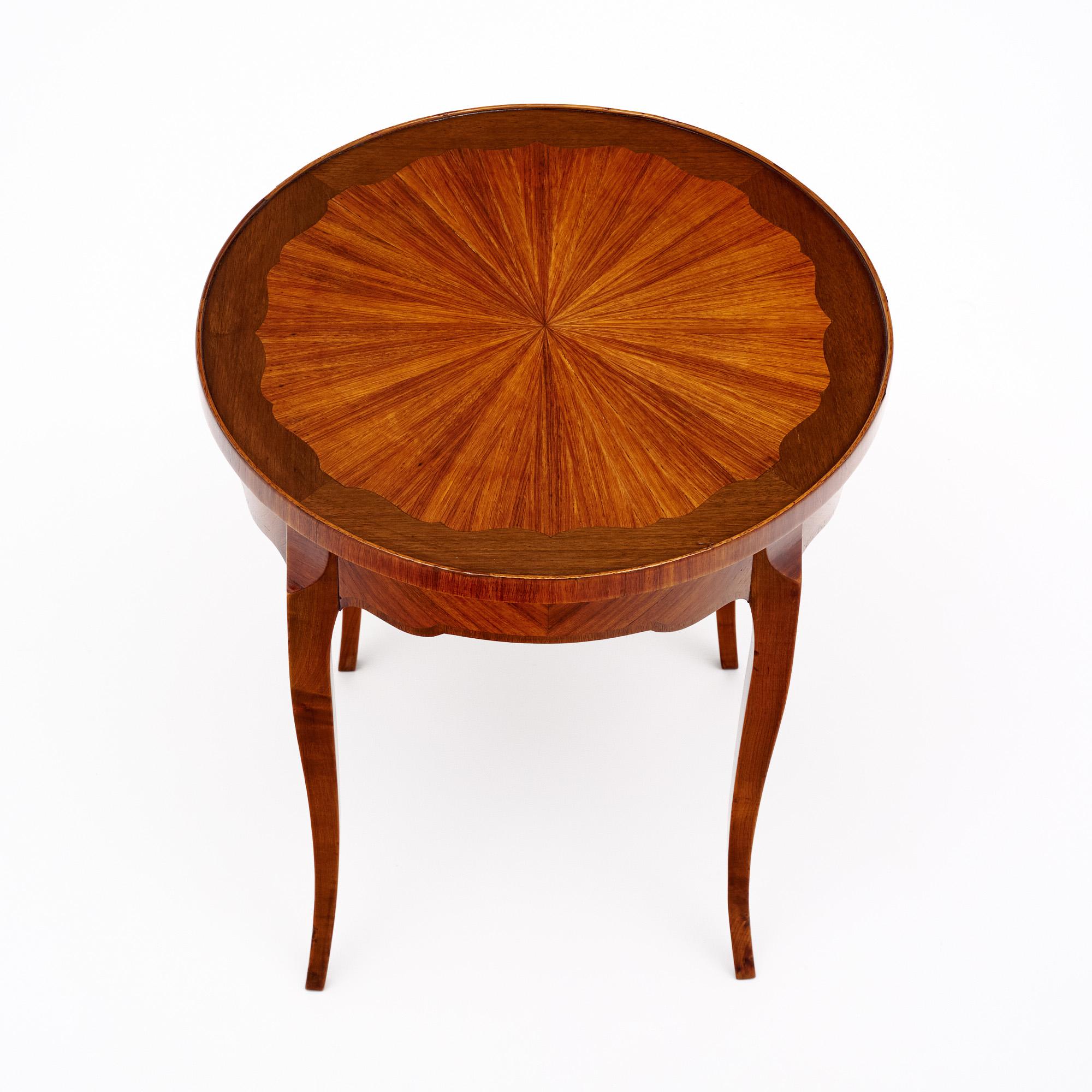 Side table from France in the transition style. This piece is made of solid wood construction, primarily cherry wood. It has been finished with a lustrous French polish of museum quality. The top is circular with a striking parquetry design