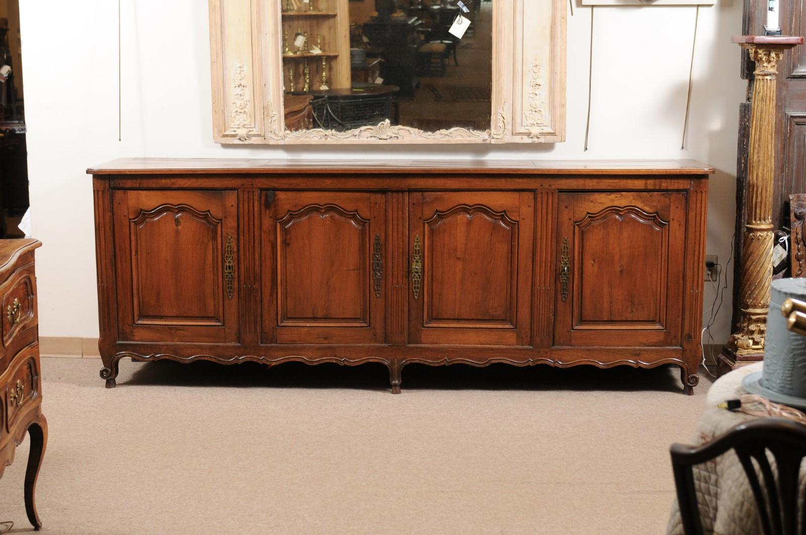 A French Transitional Louis XV/XVI style walnut Enfilade featuring fluted carving, 4 cabinet doors and 3 interior drawers, shaped apron ending on cabriole feet. 

 